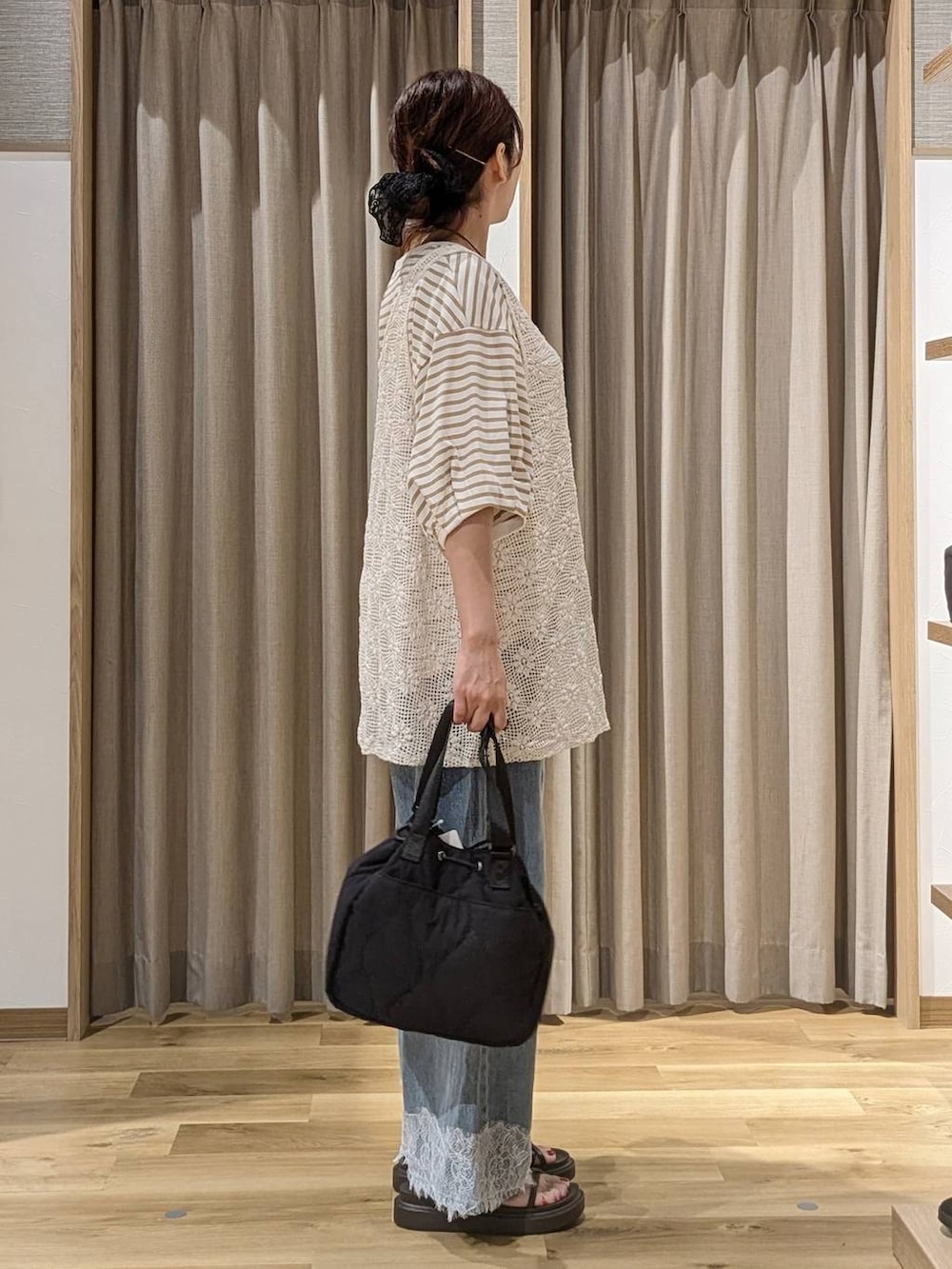 ブルー系のデニムパンツ、ブラウン系のサンダル、ホワイト系のベストを着用したレディースの夏コーディネートの2枚目の写真