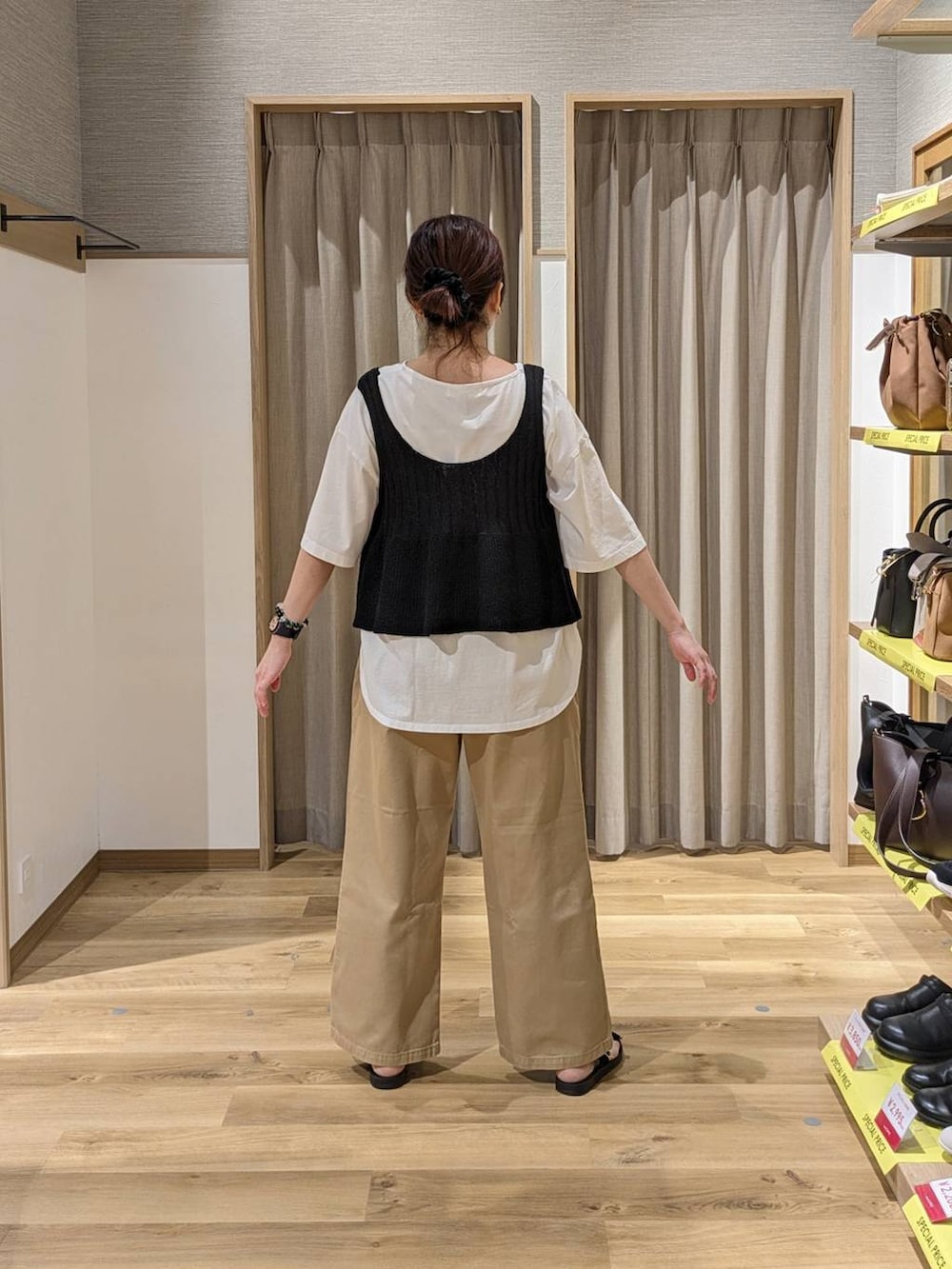 ブラウン系のショルダーバッグ、ブラック系のサンダル、ブラック系のベストを着用したレディースの春コーディネートの2枚目の写真