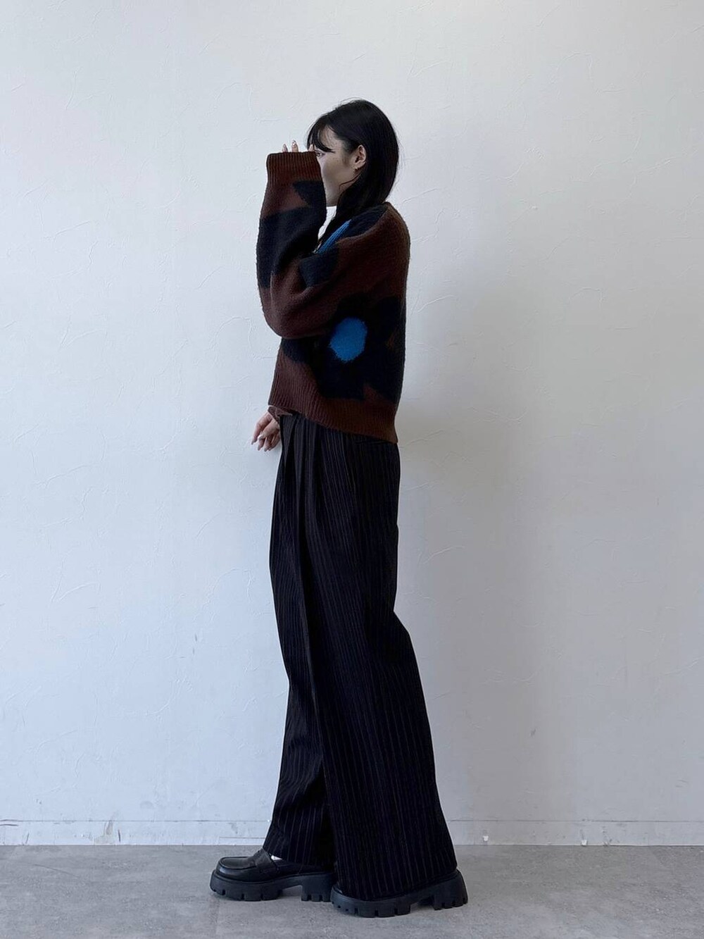 ブラック系のローファー、ブラウン系のニット/セーター、ブラック系のスラックスを着用したレディースの秋コーディネートの2枚目の写真