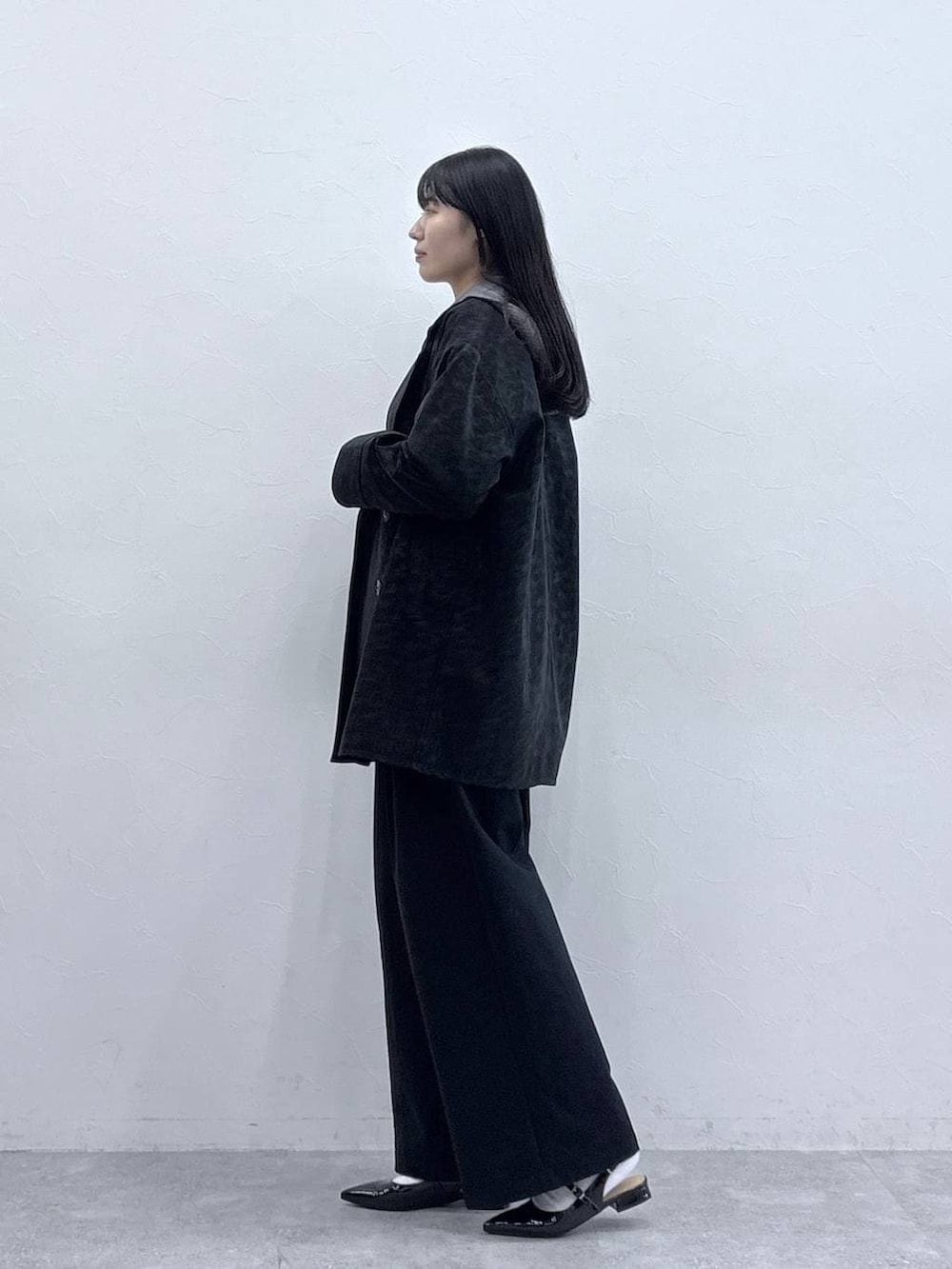グレー系のニット/セーター、ブラック系のパンプス、ブラック系のチノパンツを着用したレディースの冬コーディネートの2枚目の写真