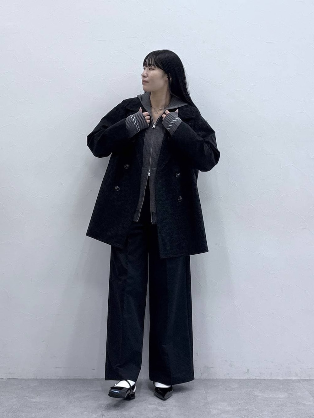 グレー系のニット/セーター、ブラック系のパンプス、ブラック系のチノパンツを着用したレディースの冬コーディネートの3枚目の写真