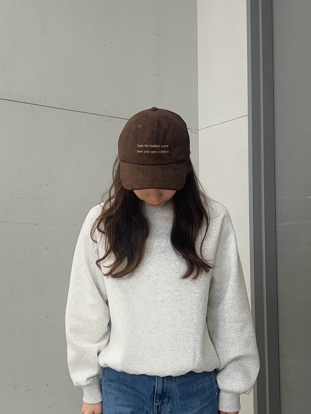 グレー系のスウェット、ブルー系のデニムパンツ、ブラック系のスニーカーを着用したレディースの秋コーディネートの3枚目の写真