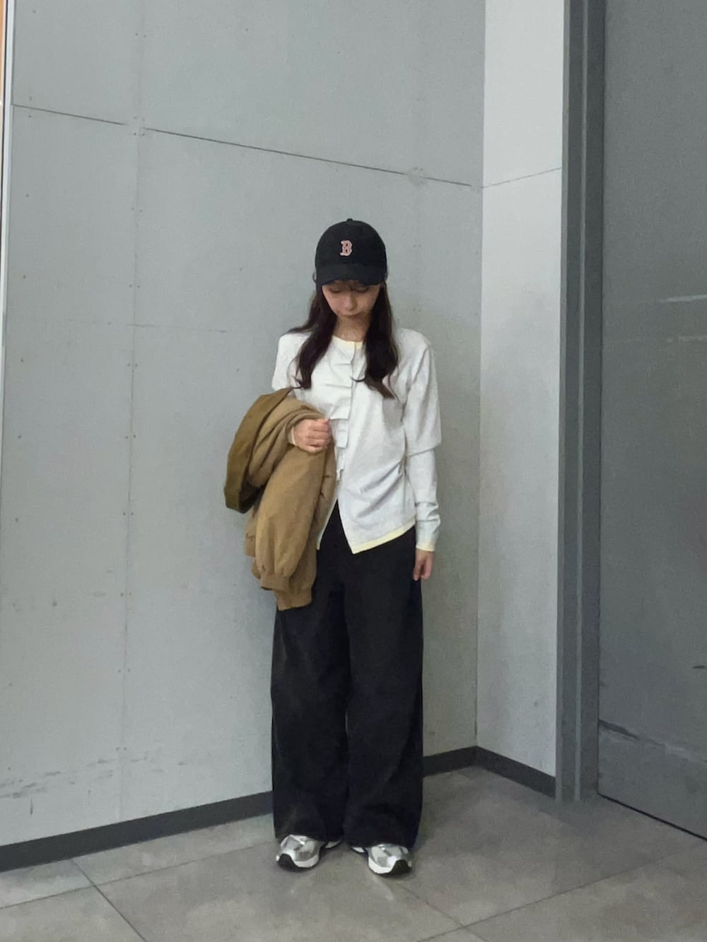 ベージュ系のTシャツ/カットソー、ベージュ系のダウンジャケット/コート、ブラック系のデニムパンツを着用したレディースの秋コーディネートの3枚目の写真