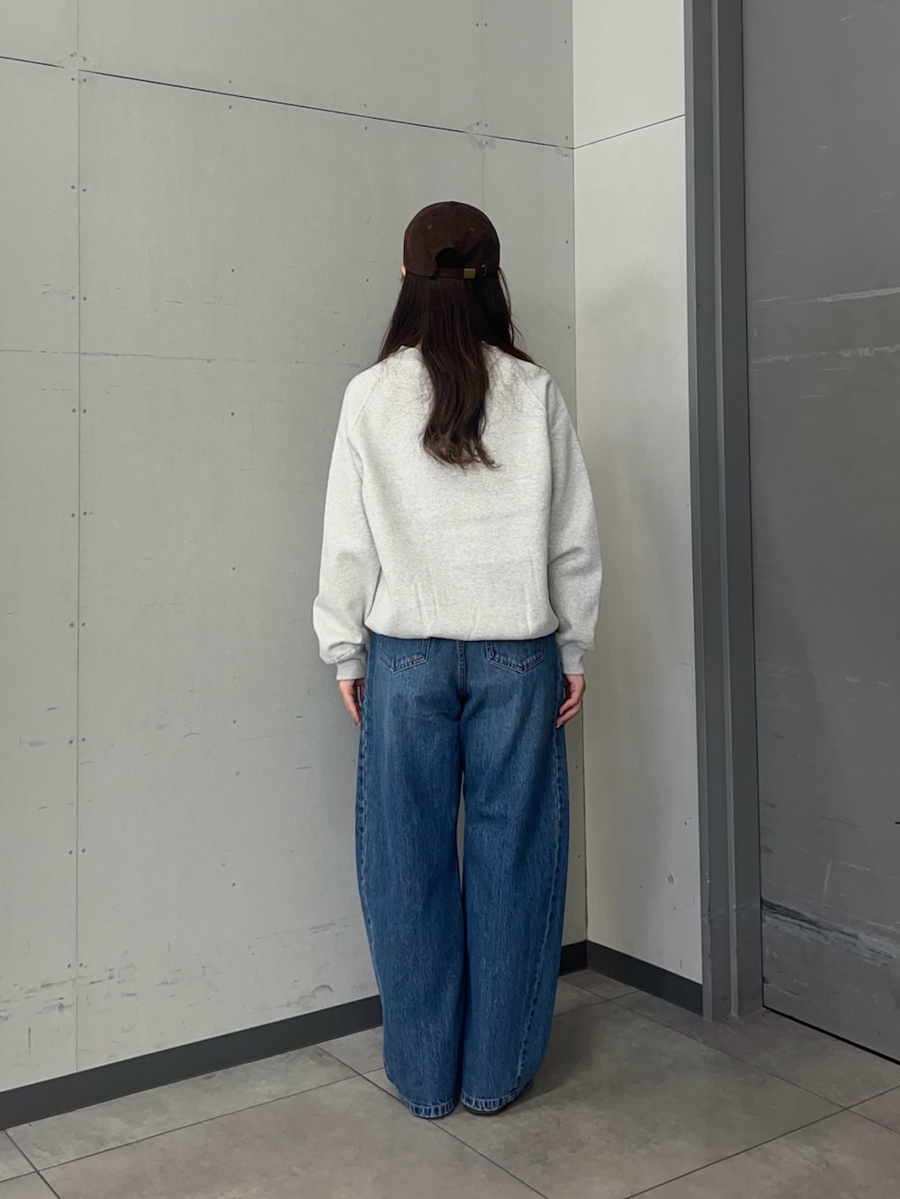 グレー系のスウェット、ブルー系のデニムパンツ、ブラック系のスニーカーを着用したレディースの秋コーディネートの4枚目の写真