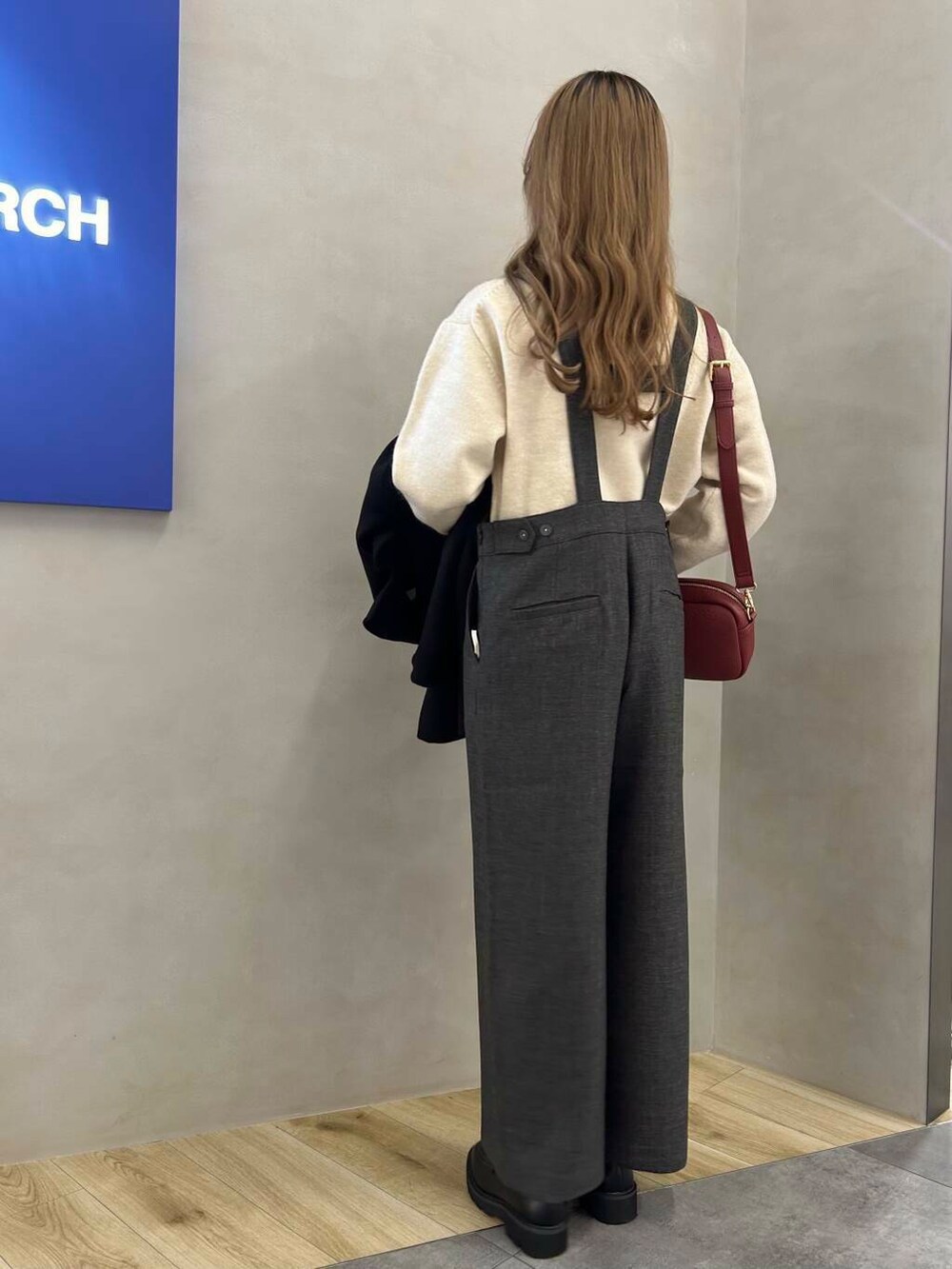 グレー系のサロペット/オーバーオール、レッド系のショルダーバッグ、ブラック系のステンカラーコートを着用したレディースの冬コーディネートの4枚目の写真