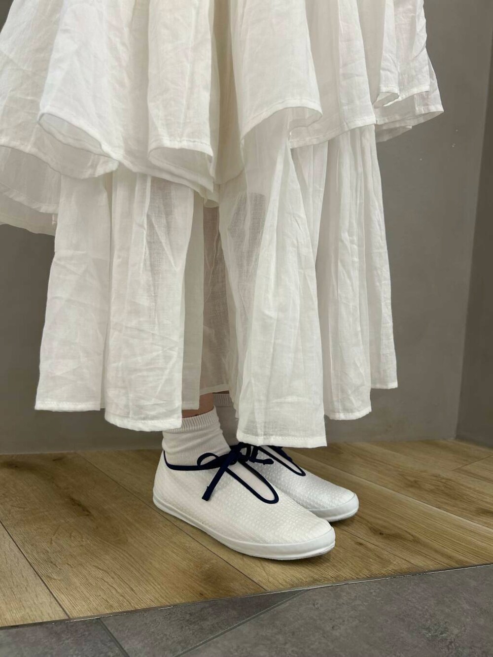 ブルー系のハンドバッグ、ブルー系のニット/セーター、ホワイト系のスカートを着用したレディースの春コーディネートの5枚目の写真