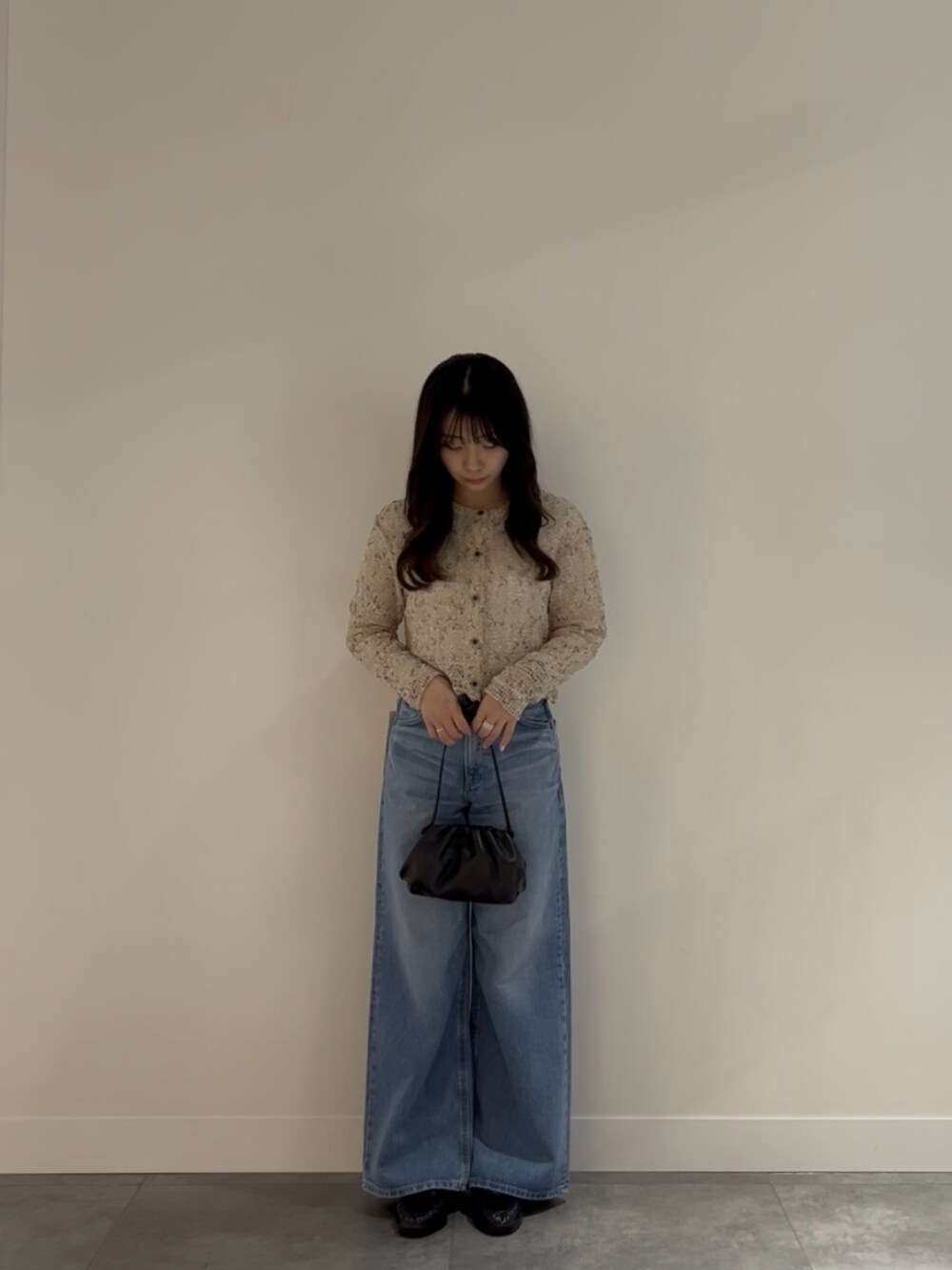 ブラック系のローファー、ブルー系のデニムパンツ、ブラック系のショルダーバッグを着用したレディースの春コーディネートの2枚目の写真
