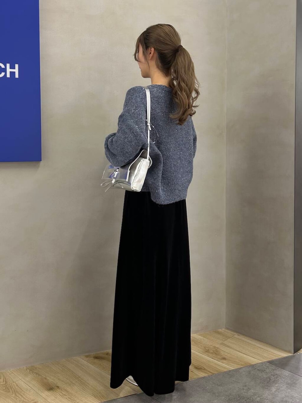 シルバー系のブーツ、ブラック系のスカート、シルバー系のショルダーバッグを着用したレディースの冬コーディネートの3枚目の写真