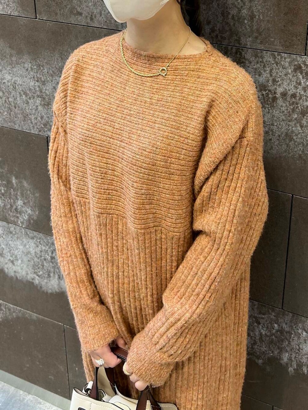 ブラック系のブーツ、ホワイト系のハンドバッグ、オレンジ系のワンピースを着用したレディースの冬コーディネートの3枚目の写真