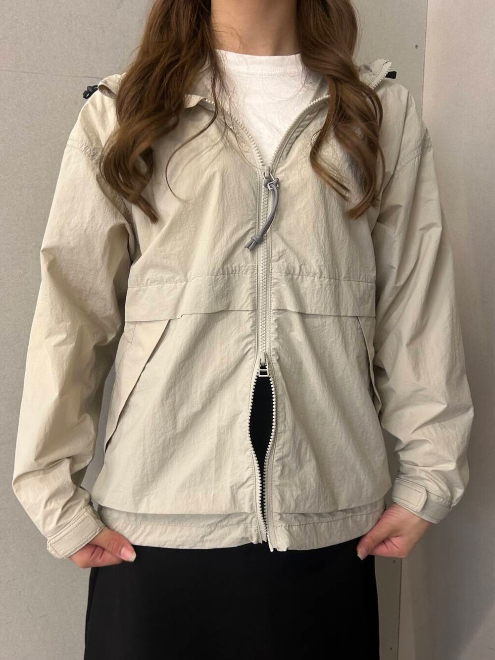 ホワイト系のTシャツ/カットソー、ブラック系のスカート、ホワイト系のナイロンジャケットを着用したレディースの春コーディネートの4枚目の写真