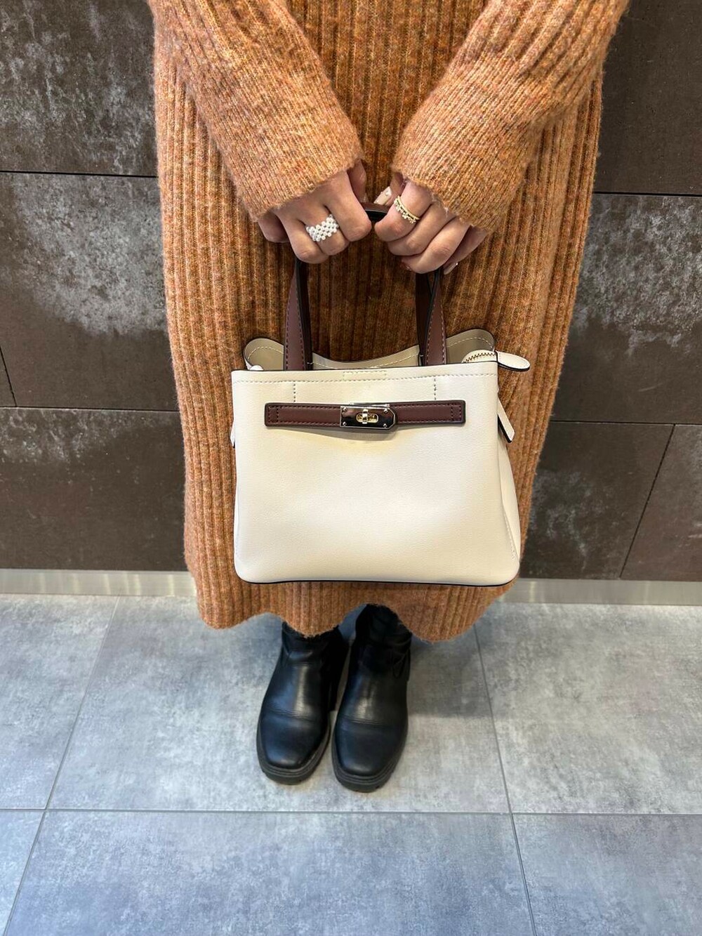 ブラック系のブーツ、ホワイト系のハンドバッグ、オレンジ系のワンピースを着用したレディースの冬コーディネートの4枚目の写真