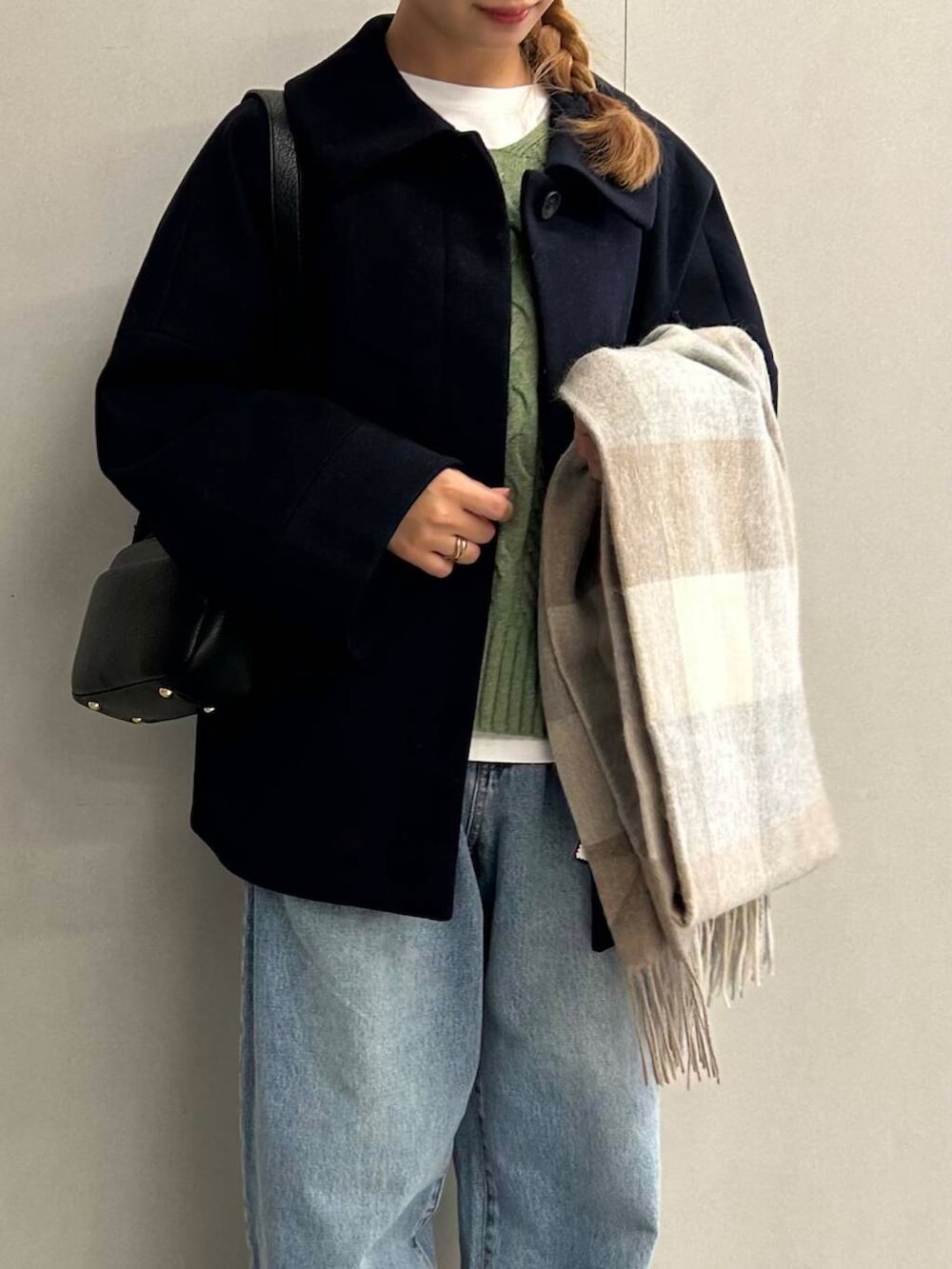 ブルー系のデニムパンツ、グリーン系のニット/セーター、ブラック系のショルダーバッグを着用したレディースの秋コーディネートの4枚目の写真