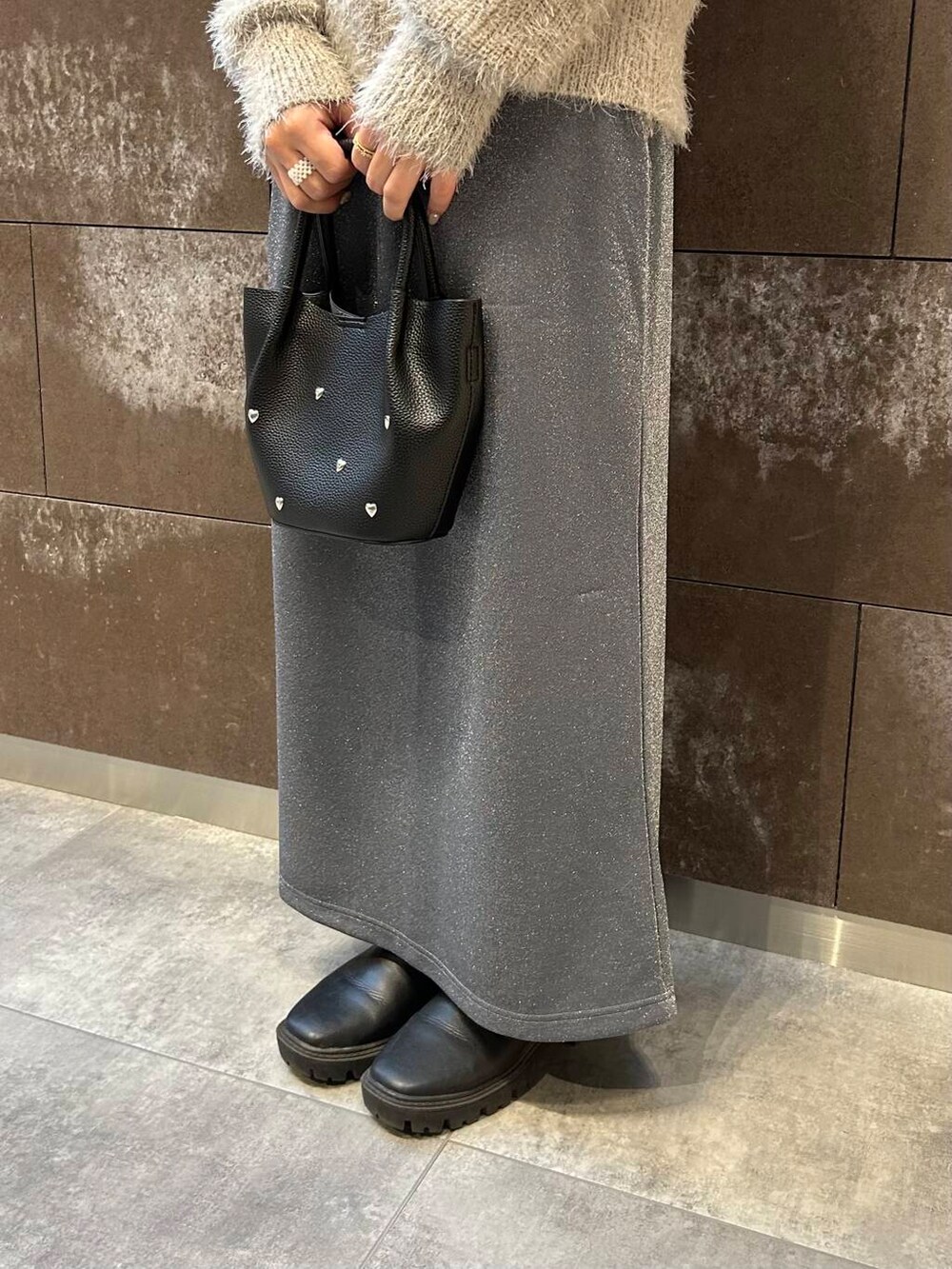 ブラック系のブーツ、グレー系のスカート、ブラック系のショルダーバッグを着用したレディースの冬コーディネートの4枚目の写真