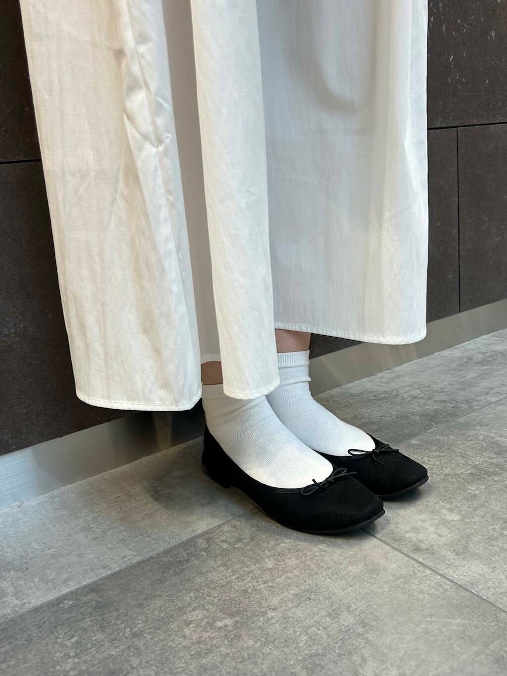 ブラック系のバレエシューズ、ブラウン系のボストンバッグ、ブラック系のワンピースを着用したレディースの冬コーディネートの5枚目の写真