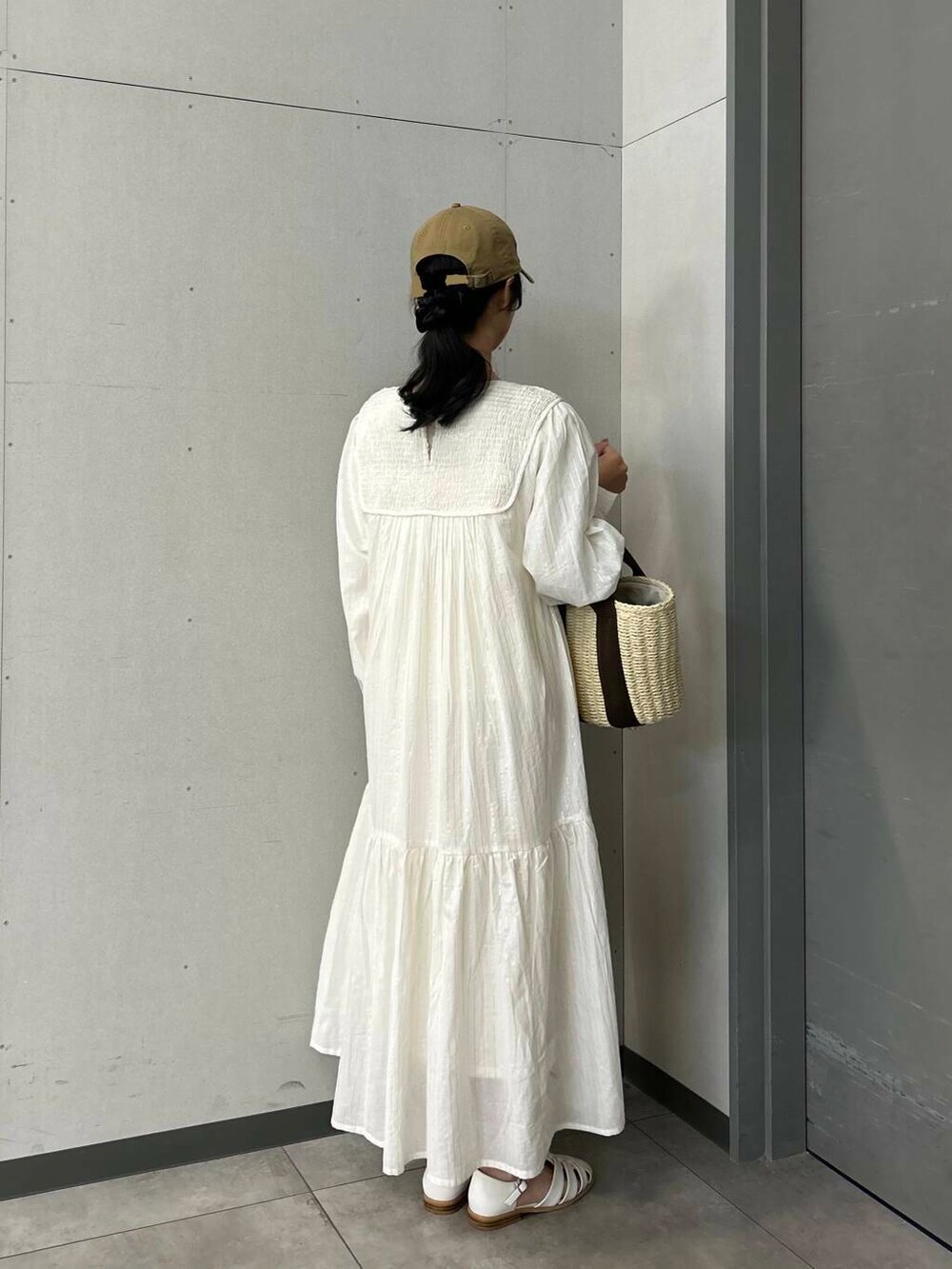 ホワイト系のハンドバッグ、ホワイト系のサンダル、ベージュ系のワンピースを着用したレディースの春コーディネートの2枚目の写真