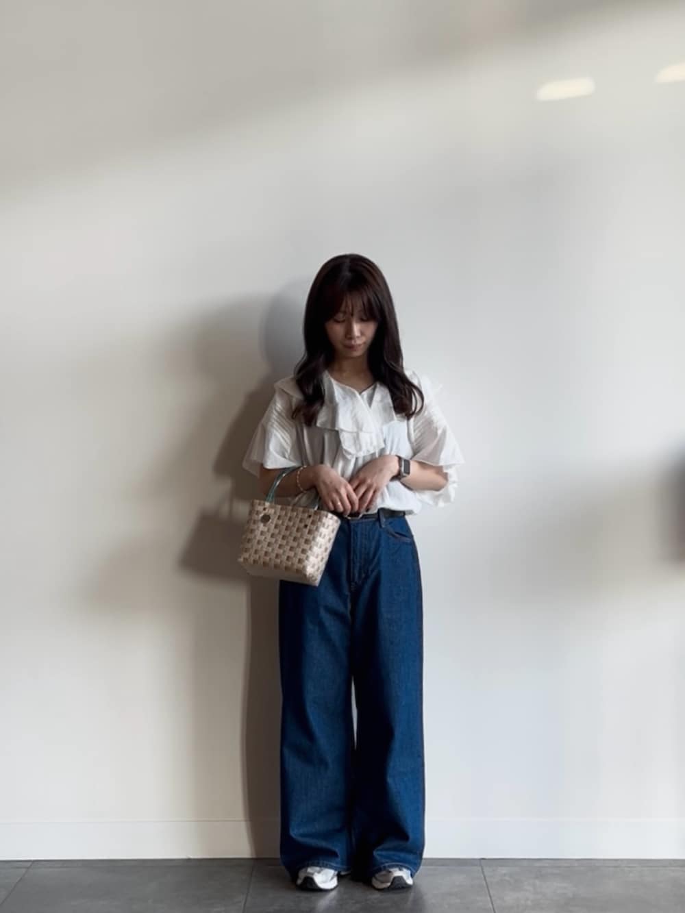 ブルー系のデニムパンツ、ホワイト系のシャツ/ブラウス、ベージュ系のショルダーバッグを着用したレディースの夏コーディネートの2枚目の写真