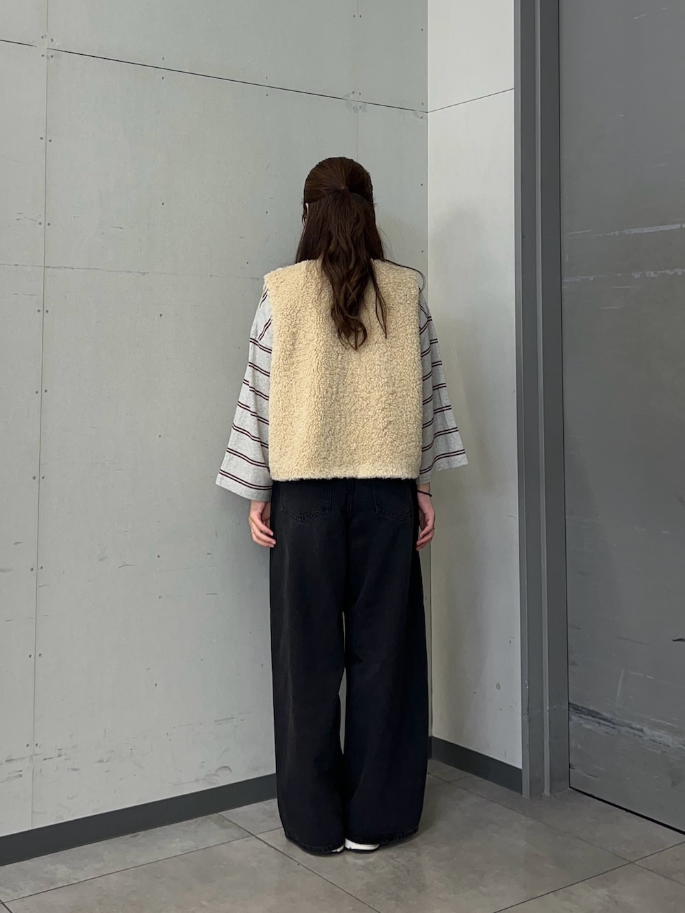 グレー系のTシャツ/カットソー、ベージュ系のダウンベスト、ブラック系のデニムパンツを着用したレディースの秋コーディネートの3枚目の写真
