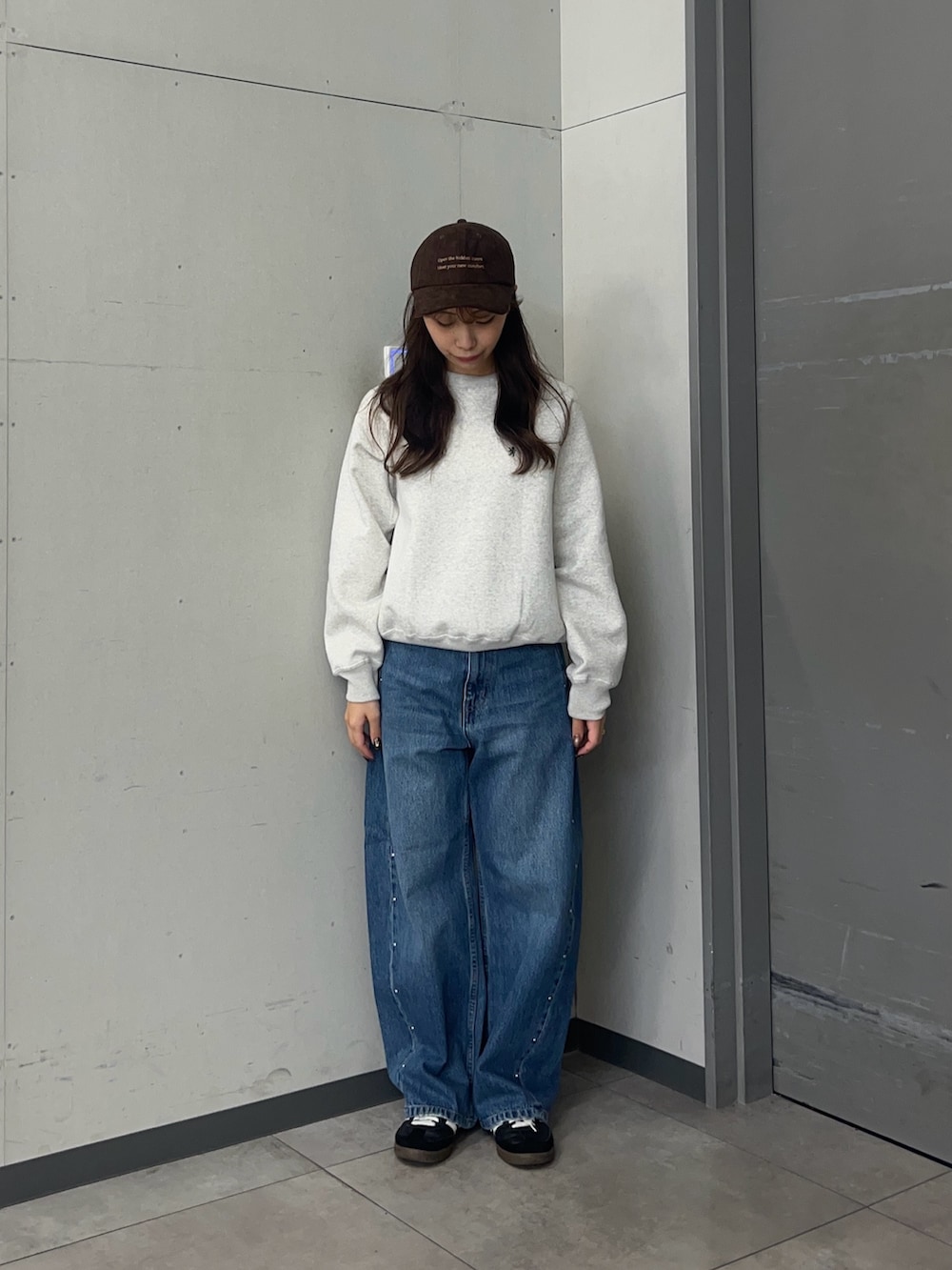 グレー系のスウェット、ブルー系のデニムパンツ、ブラック系のスニーカーを着用したレディースの秋コーディネートの2枚目の写真