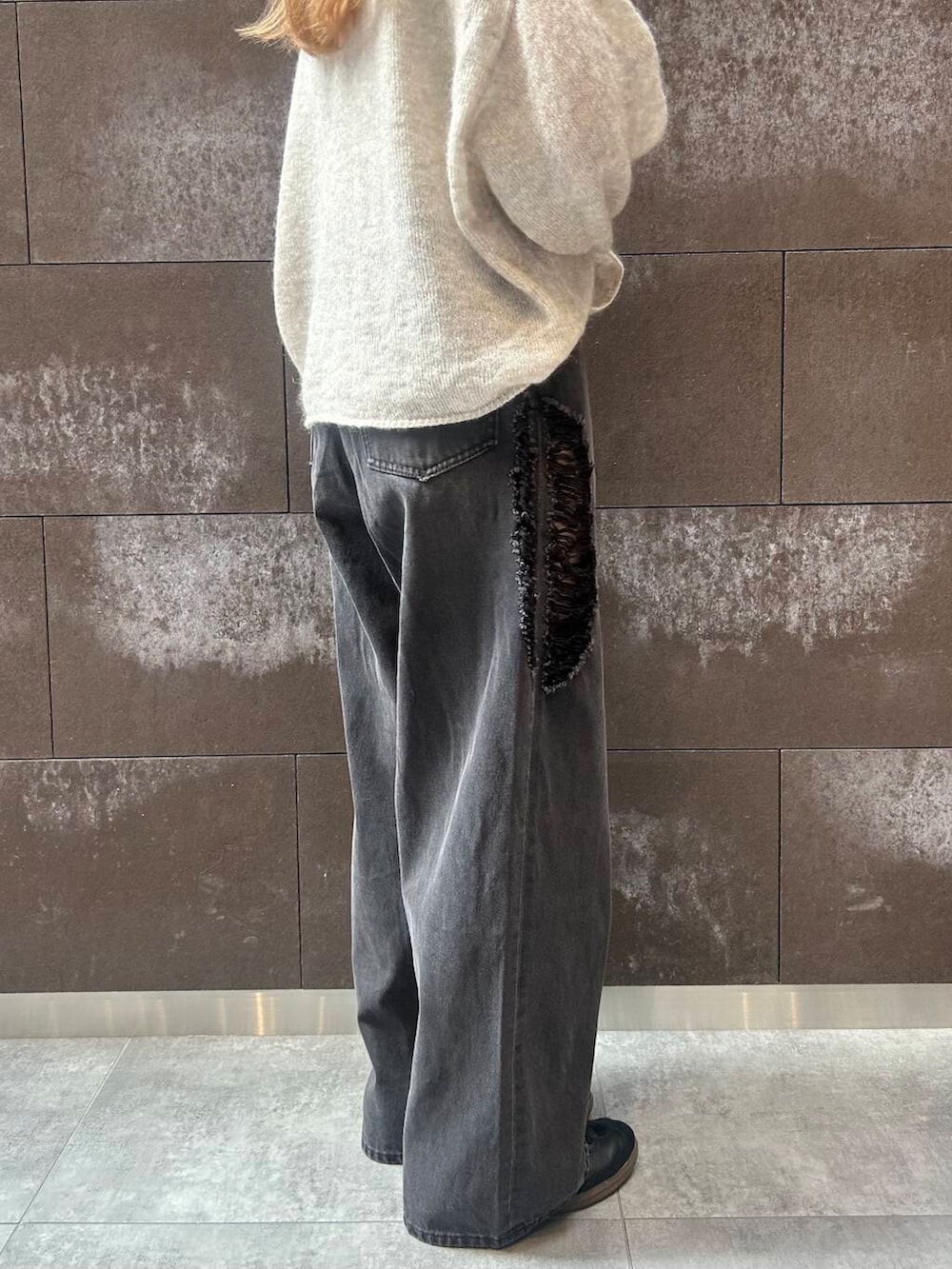 ブラック系のスニーカー、レッド系のボストンバッグ、ブラック系のデニムパンツを着用したレディースの秋コーディネートの4枚目の写真