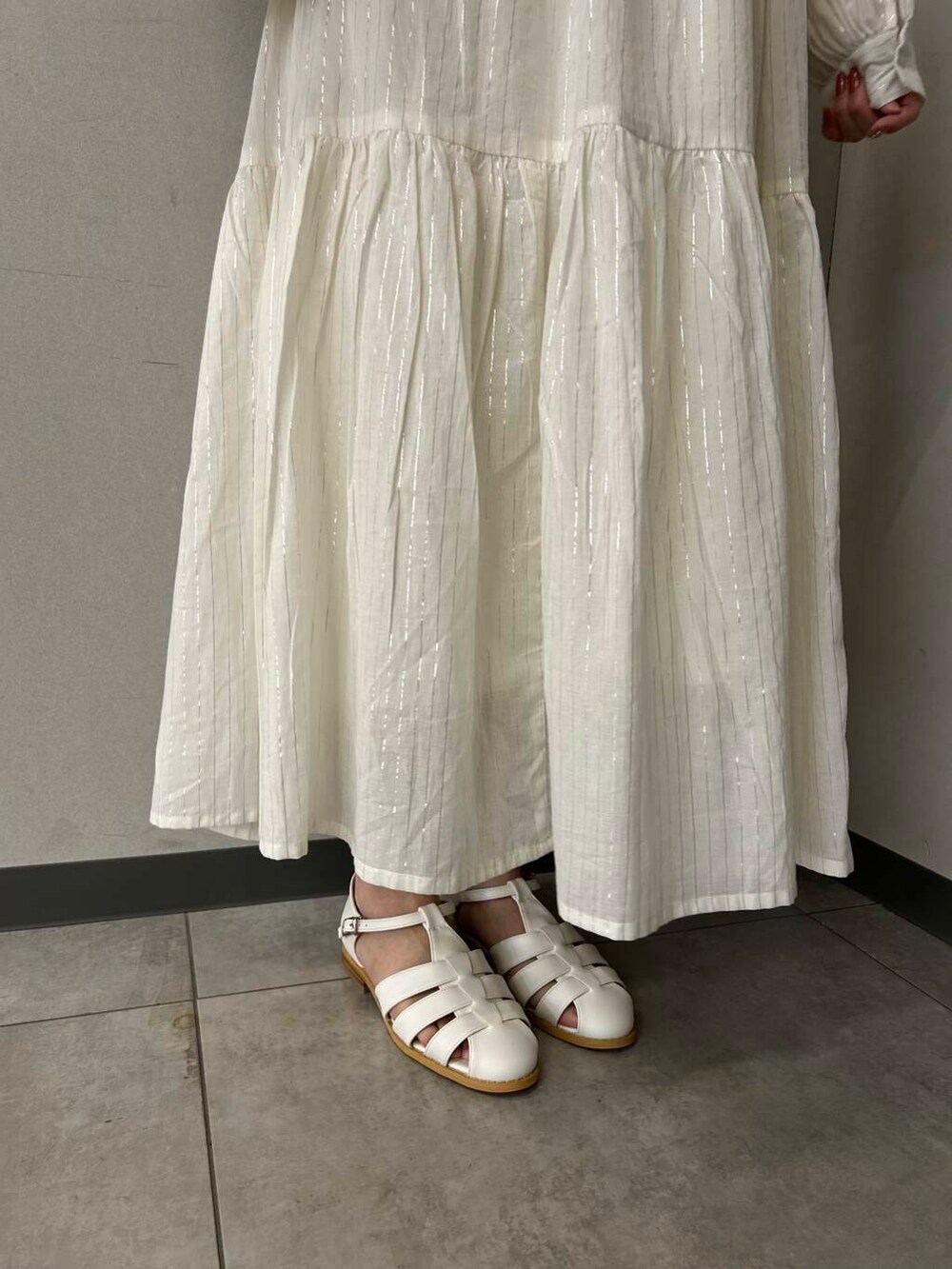 ホワイト系のハンドバッグ、ホワイト系のサンダル、ベージュ系のワンピースを着用したレディースの春コーディネートの5枚目の写真