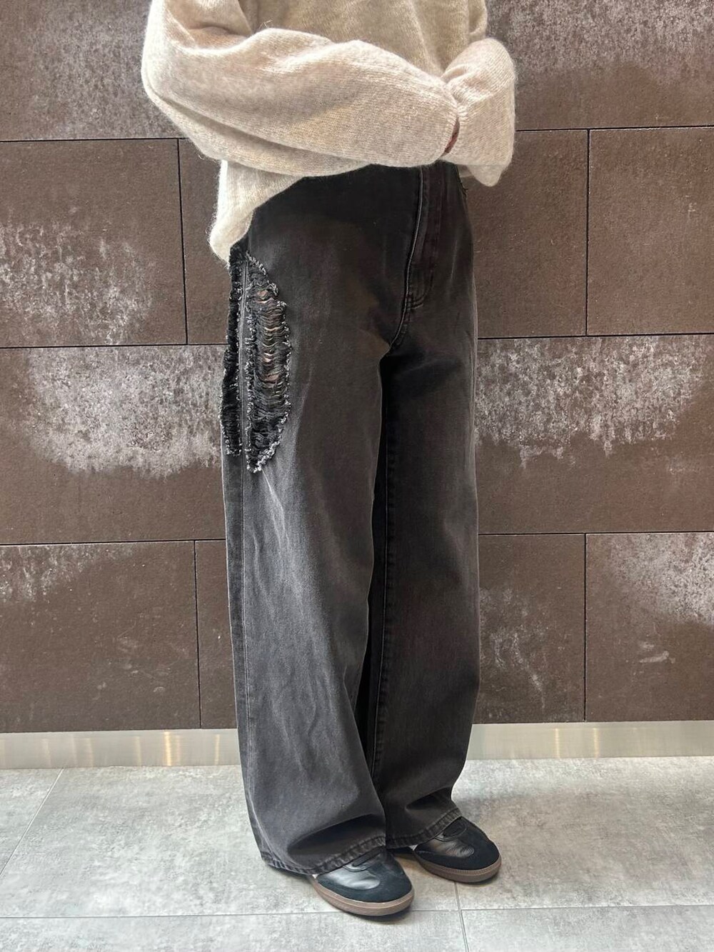 ブラック系のスニーカー、レッド系のボストンバッグ、ブラック系のデニムパンツを着用したレディースの秋コーディネートの3枚目の写真