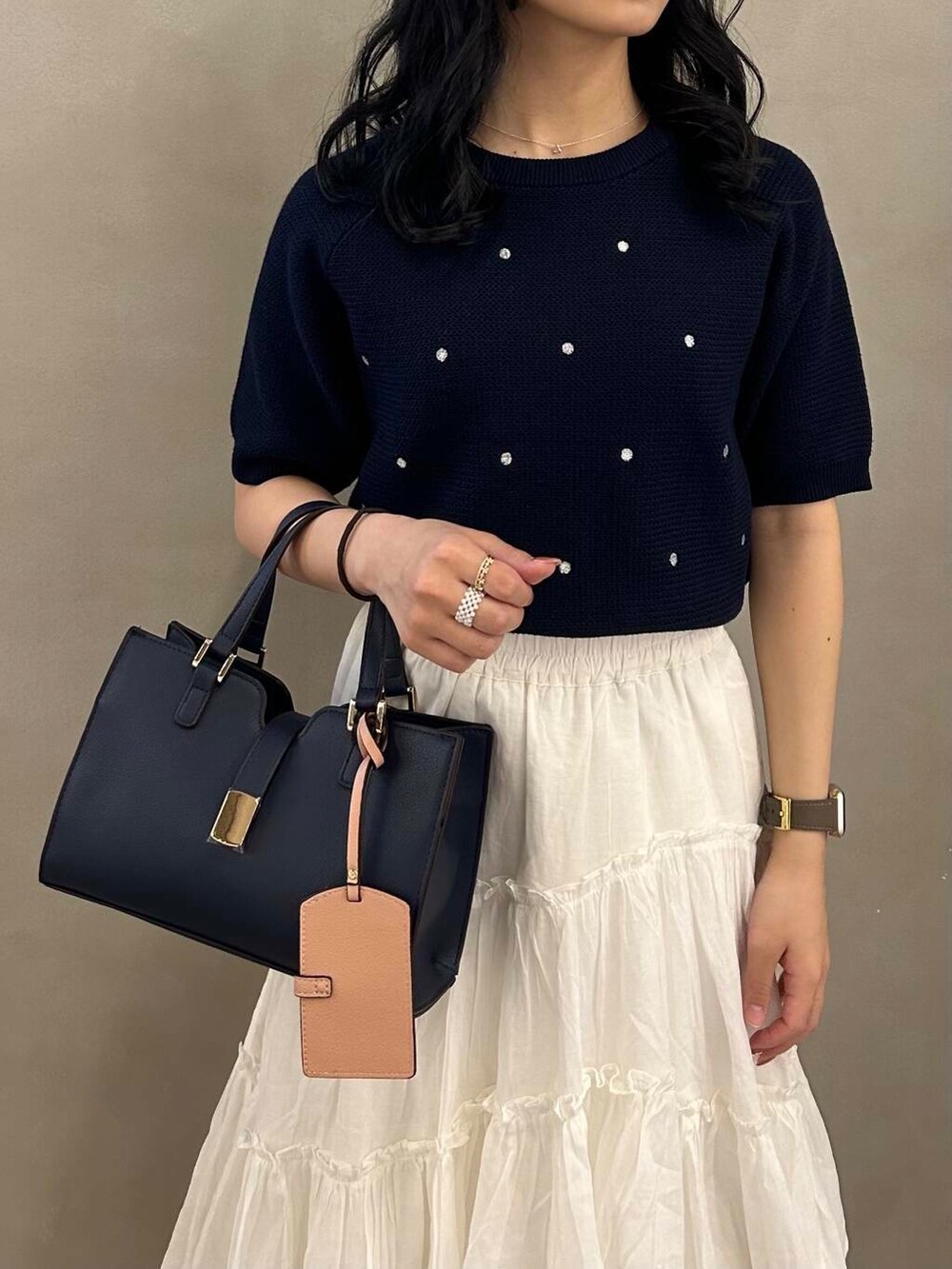 ブルー系のハンドバッグ、ブルー系のニット/セーター、ホワイト系のスカートを着用したレディースの春コーディネートの3枚目の写真