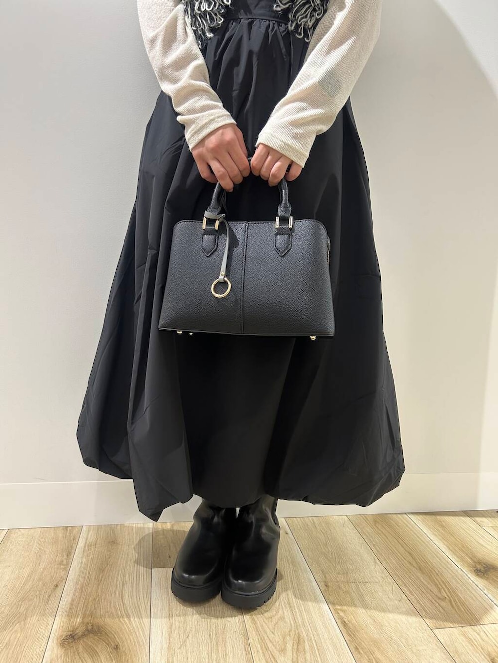 ブラック系のベスト、ブラック系のスカート、ブラック系のブーツを着用したレディースの秋コーディネートの4枚目の写真