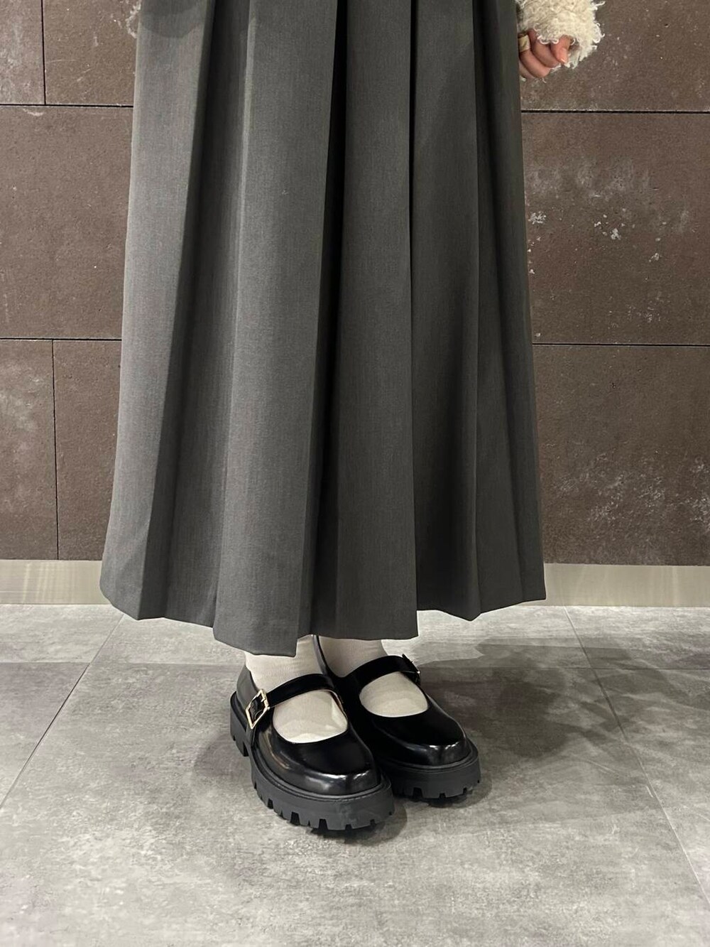 グレー系のスカート、ブラック系のその他シューズ、ホワイト系のニット/セーターを着用したレディースの秋コーディネートの6枚目の写真