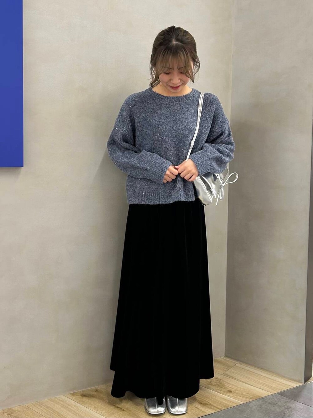 シルバー系のブーツ、ブラック系のスカート、シルバー系のショルダーバッグを着用したレディースの冬コーディネートの2枚目の写真