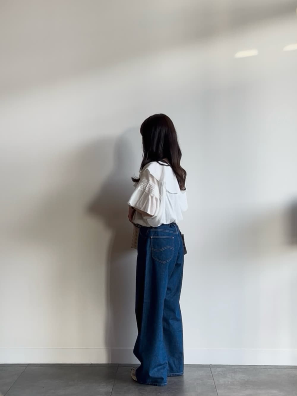 ブルー系のデニムパンツ、ホワイト系のシャツ/ブラウス、ベージュ系のショルダーバッグを着用したレディースの夏コーディネートの3枚目の写真