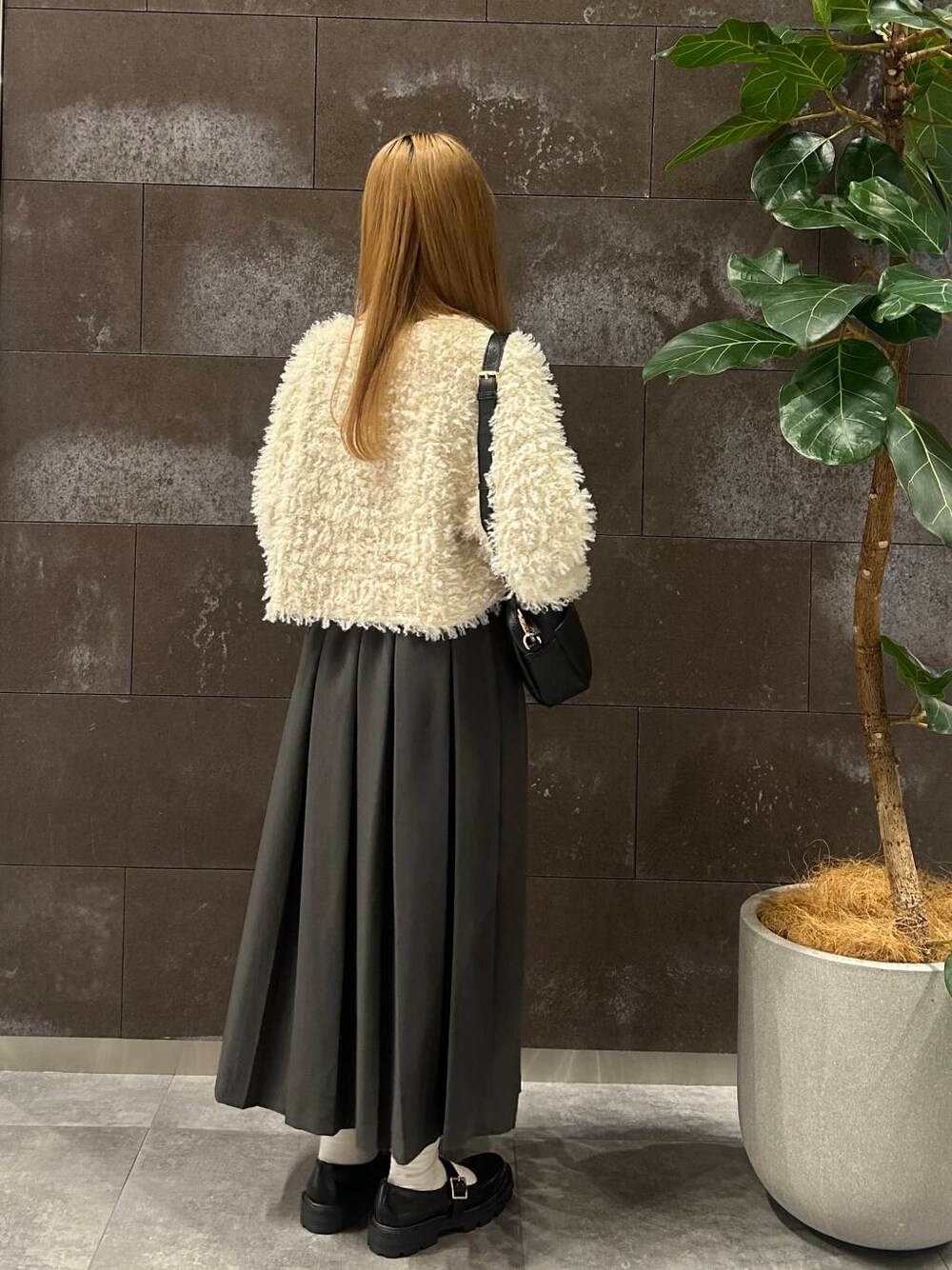 グレー系のスカート、ブラック系のその他シューズ、ホワイト系のニット/セーターを着用したレディースの秋コーディネートの2枚目の写真