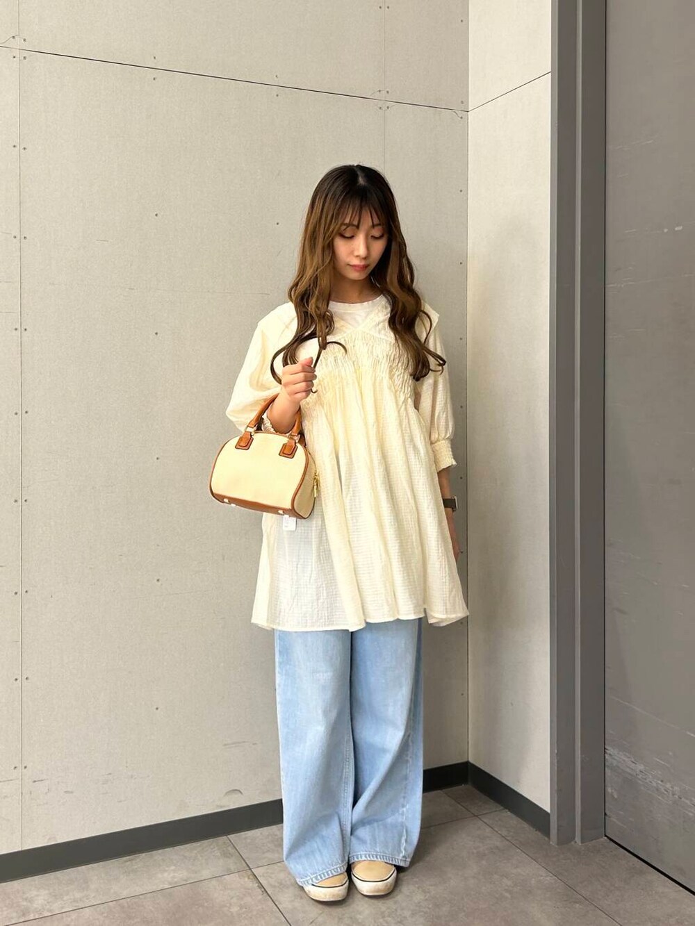 イエロー系のボストンバッグ、ホワイト系のワンピースを着用したレディースの春コーディネートの2枚目の写真