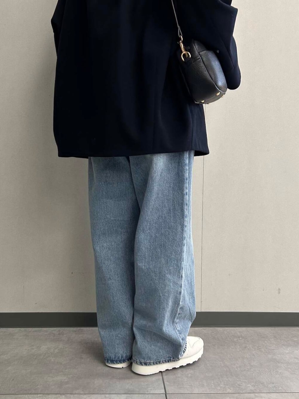 ブルー系のデニムパンツ、グリーン系のニット/セーター、ブラック系のショルダーバッグを着用したレディースの秋コーディネートの5枚目の写真