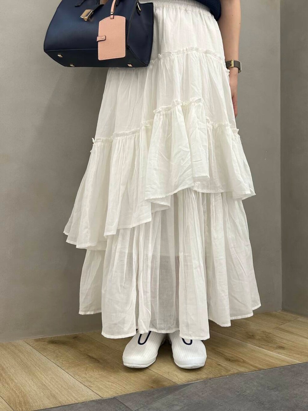 ブルー系のハンドバッグ、ブルー系のニット/セーター、ホワイト系のスカートを着用したレディースの春コーディネートの4枚目の写真