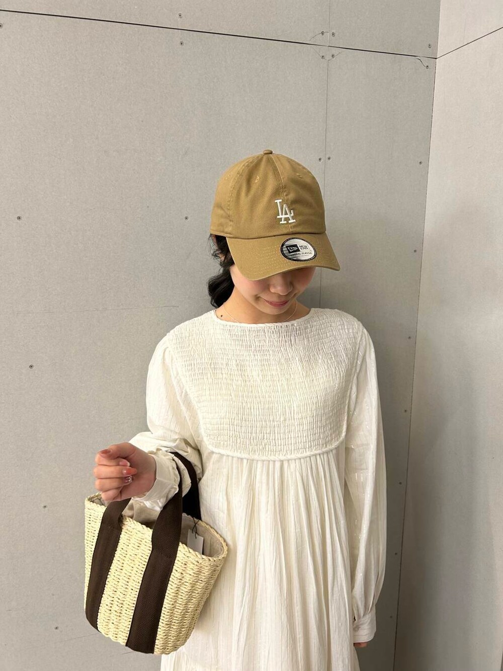 ホワイト系のハンドバッグ、ホワイト系のサンダル、ベージュ系のワンピースを着用したレディースの春コーディネートの3枚目の写真