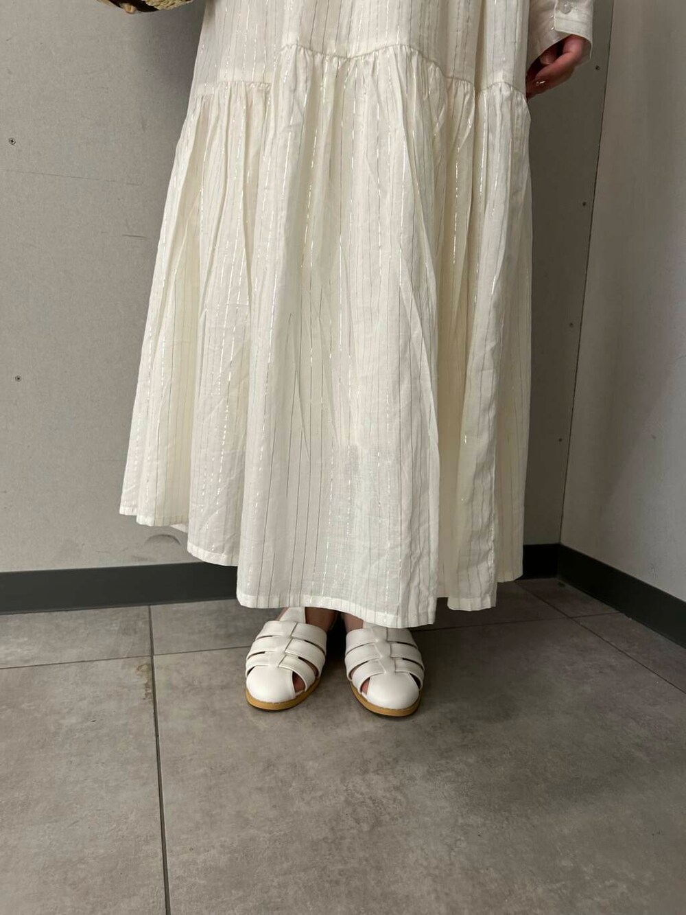 ホワイト系のハンドバッグ、ホワイト系のサンダル、ベージュ系のワンピースを着用したレディースの春コーディネートの4枚目の写真