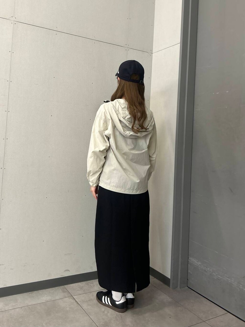 ホワイト系のTシャツ/カットソー、ブラック系のスカート、ホワイト系のナイロンジャケットを着用したレディースの春コーディネートの3枚目の写真