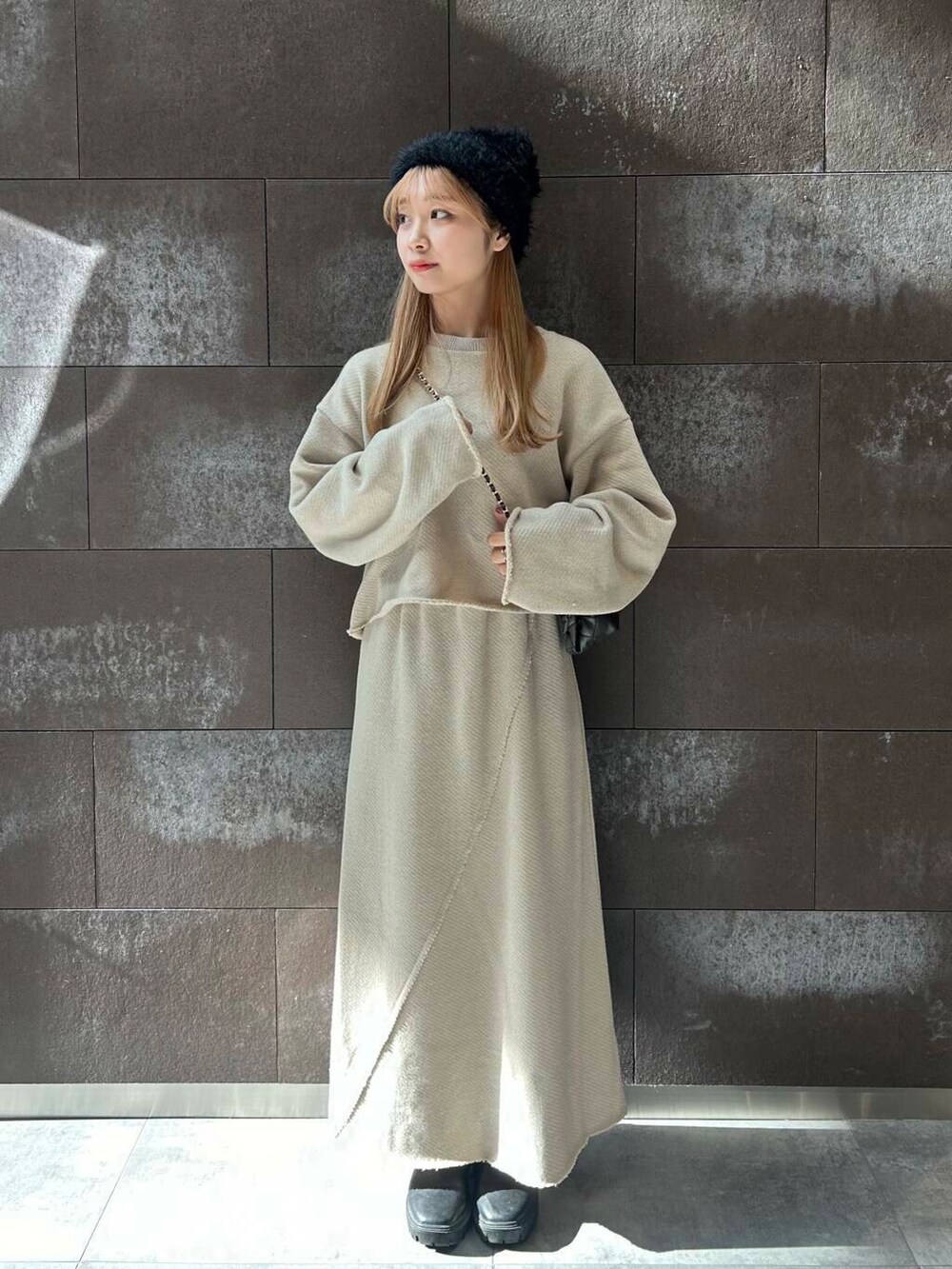 ベージュ系のTシャツ/カットソー、ベージュ系のスカート、ブラック系のショルダーバッグを着用したレディースの秋コーディネートの2枚目の写真