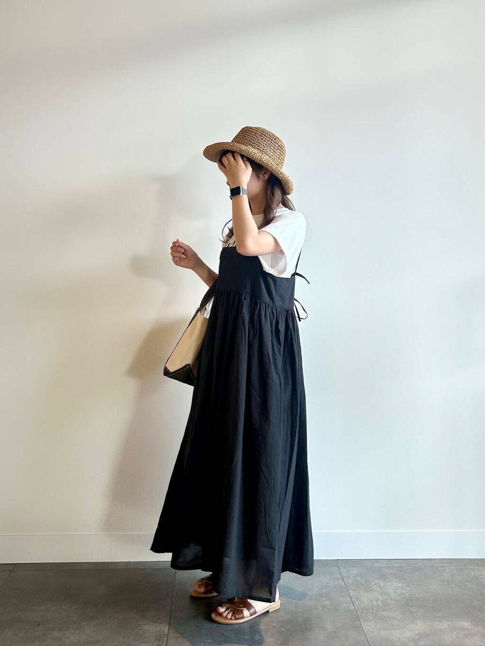 ブラウン系のサンダル、ブラック系のワンピース、ホワイト系のTシャツ/カットソーを着用したレディースの夏コーディネートの2枚目の写真