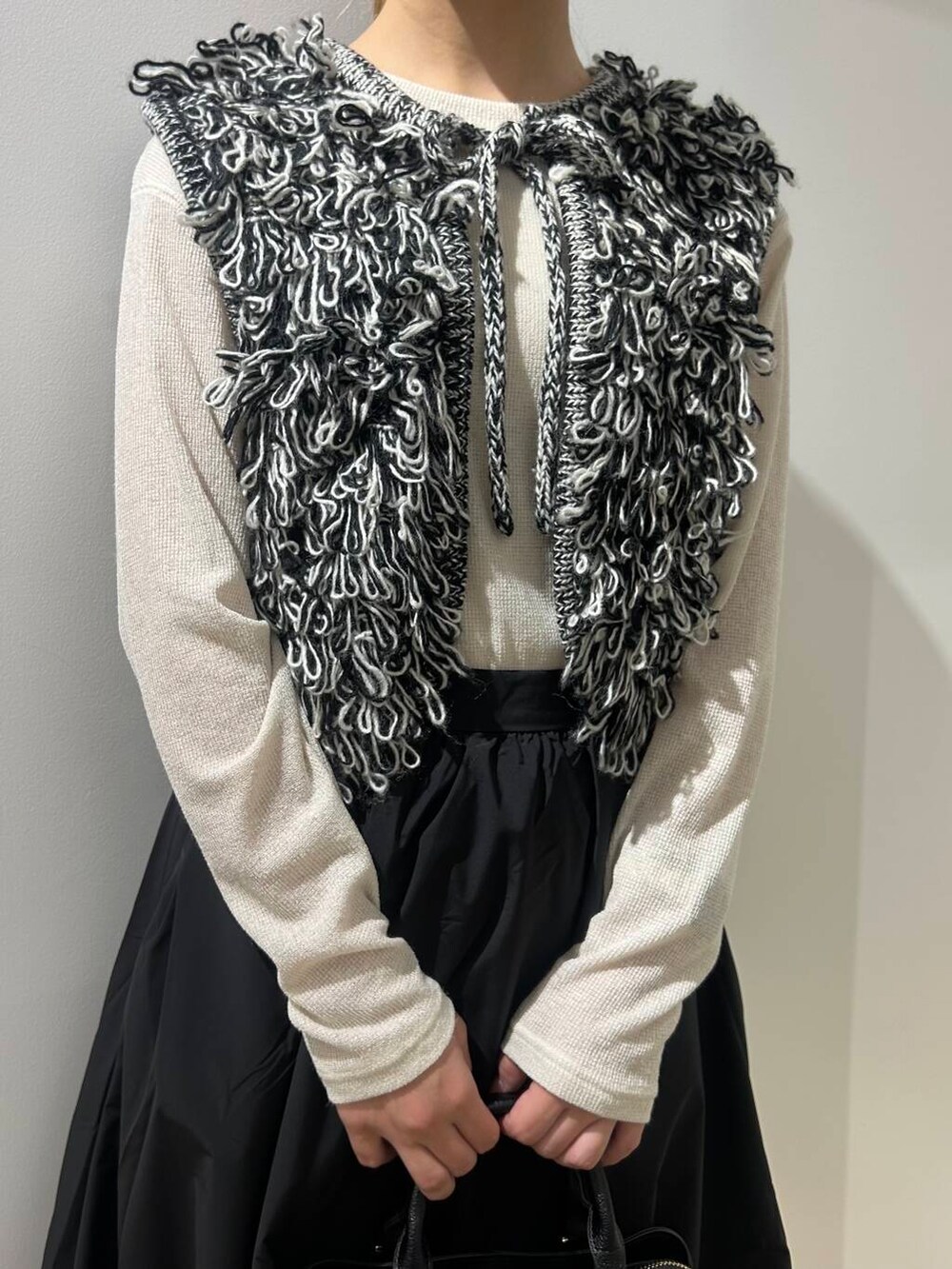 ブラック系のベスト、ブラック系のスカート、ブラック系のブーツを着用したレディースの秋コーディネートの3枚目の写真