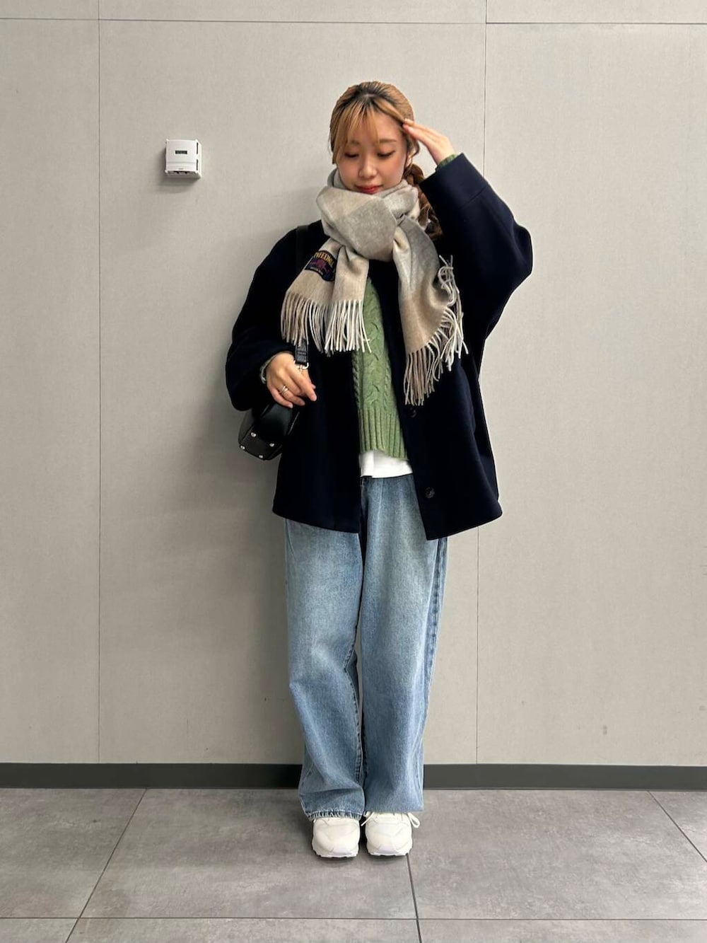 ブルー系のデニムパンツ、グリーン系のニット/セーター、ブラック系のショルダーバッグを着用したレディースの秋コーディネートの2枚目の写真