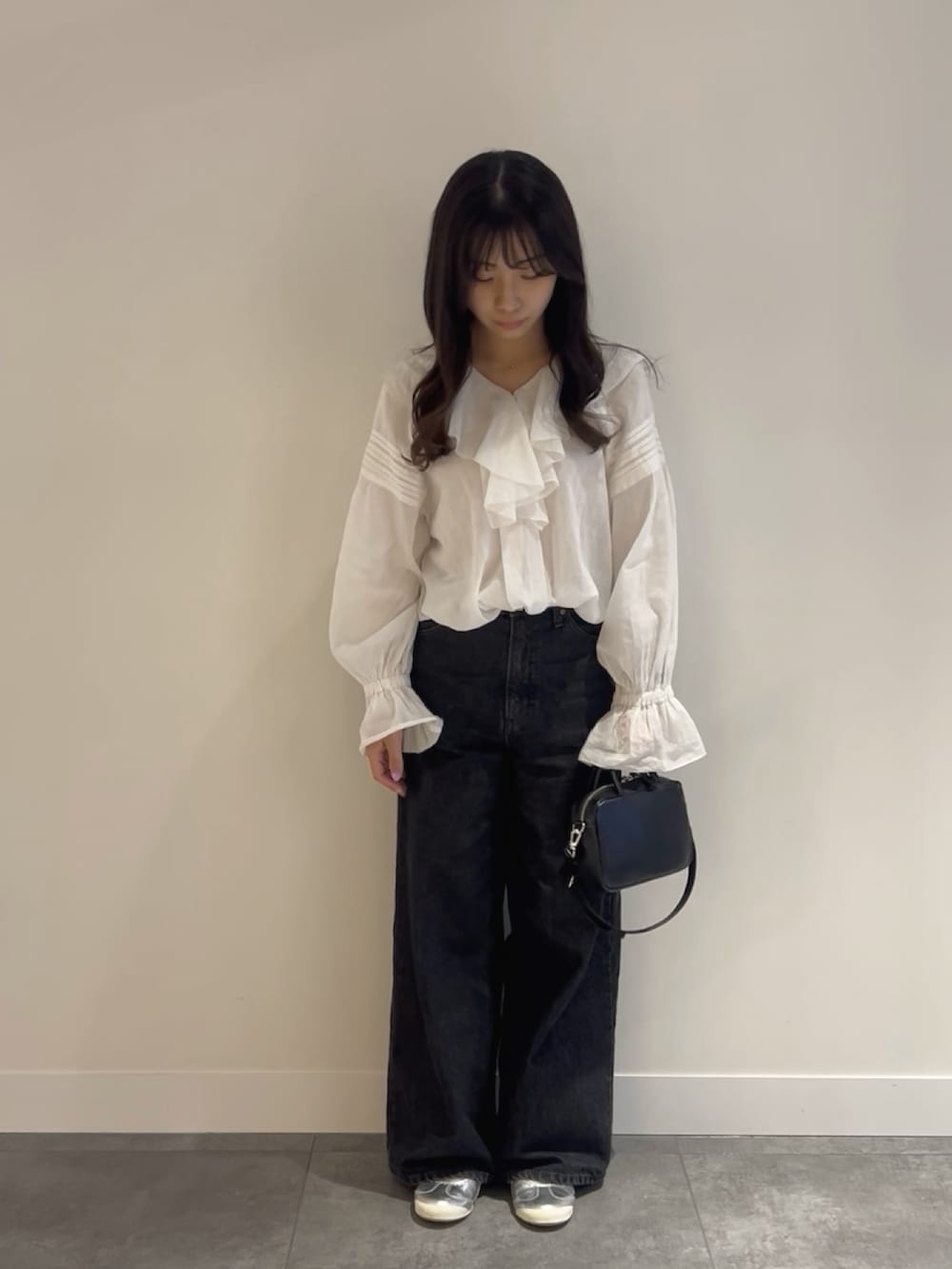 ブラック系のデニムパンツ、ブラック系のショルダーバッグ、ホワイト系のシャツ/ブラウスを着用したレディースの春コーディネートの2枚目の写真