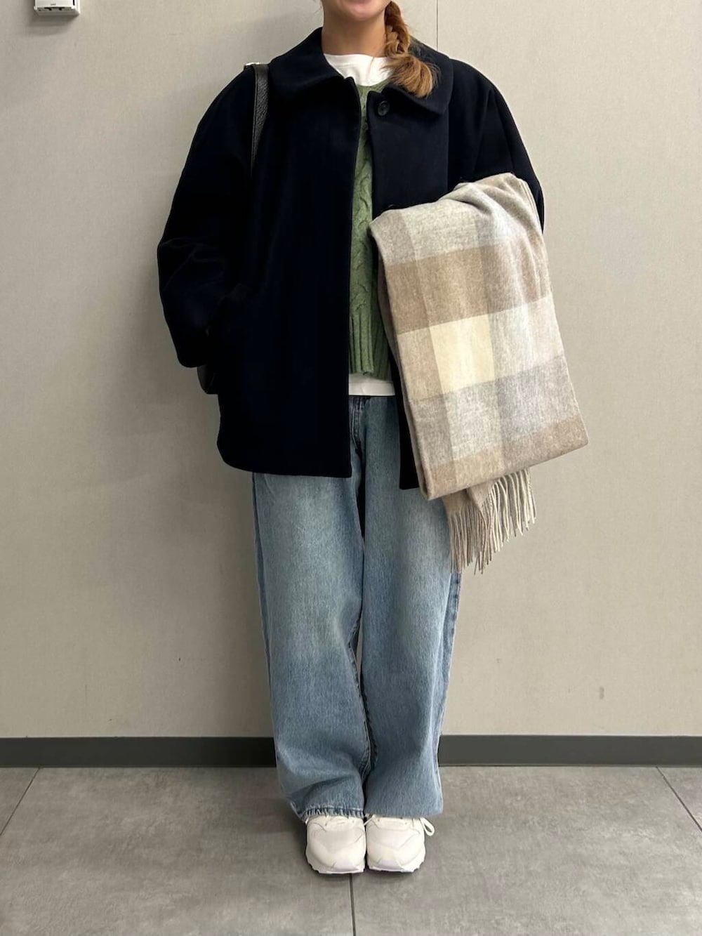 ブルー系のデニムパンツ、グリーン系のニット/セーター、ブラック系のショルダーバッグを着用したレディースの秋コーディネートの3枚目の写真