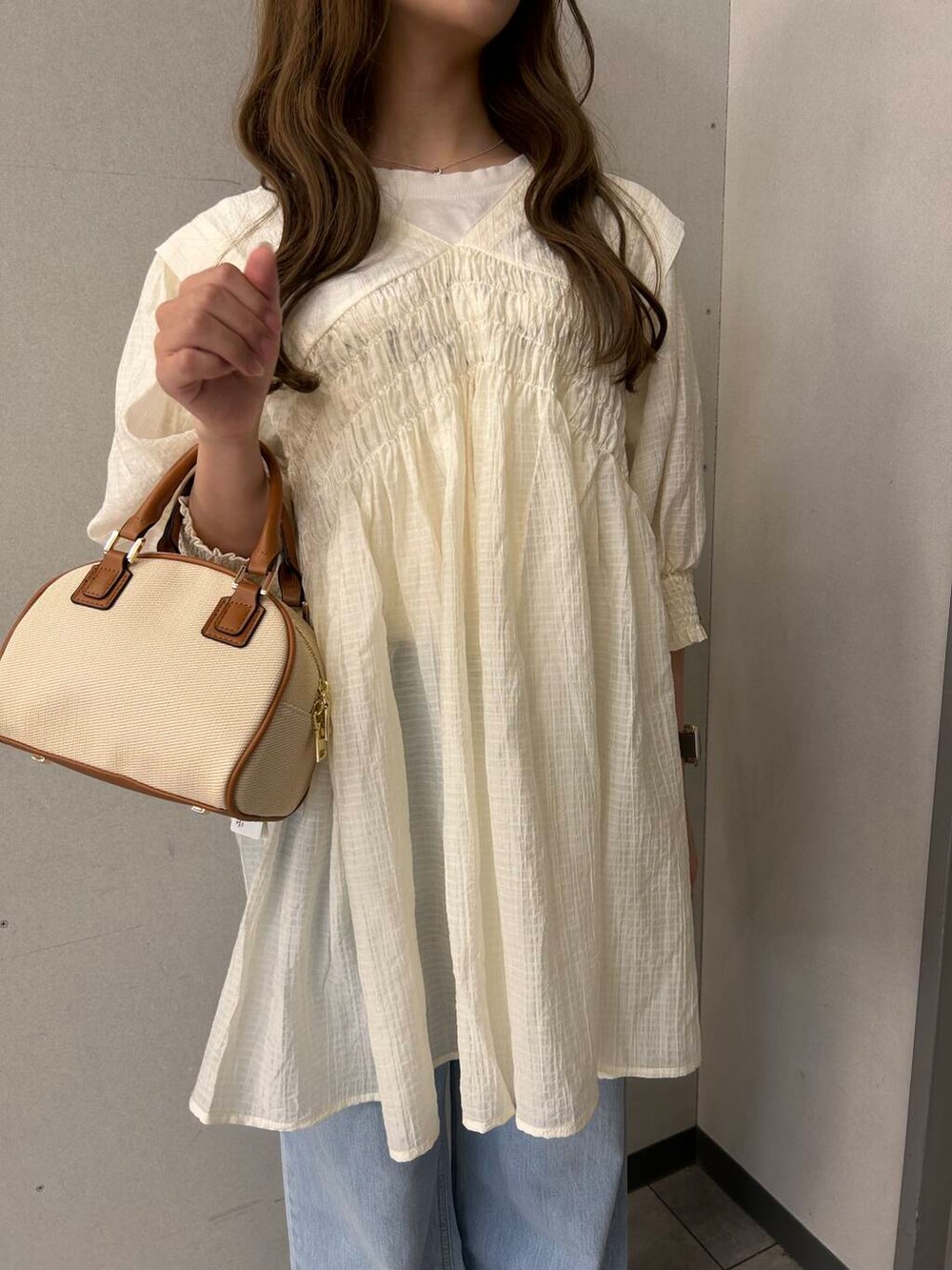 イエロー系のボストンバッグ、ホワイト系のワンピースを着用したレディースの春コーディネートの4枚目の写真