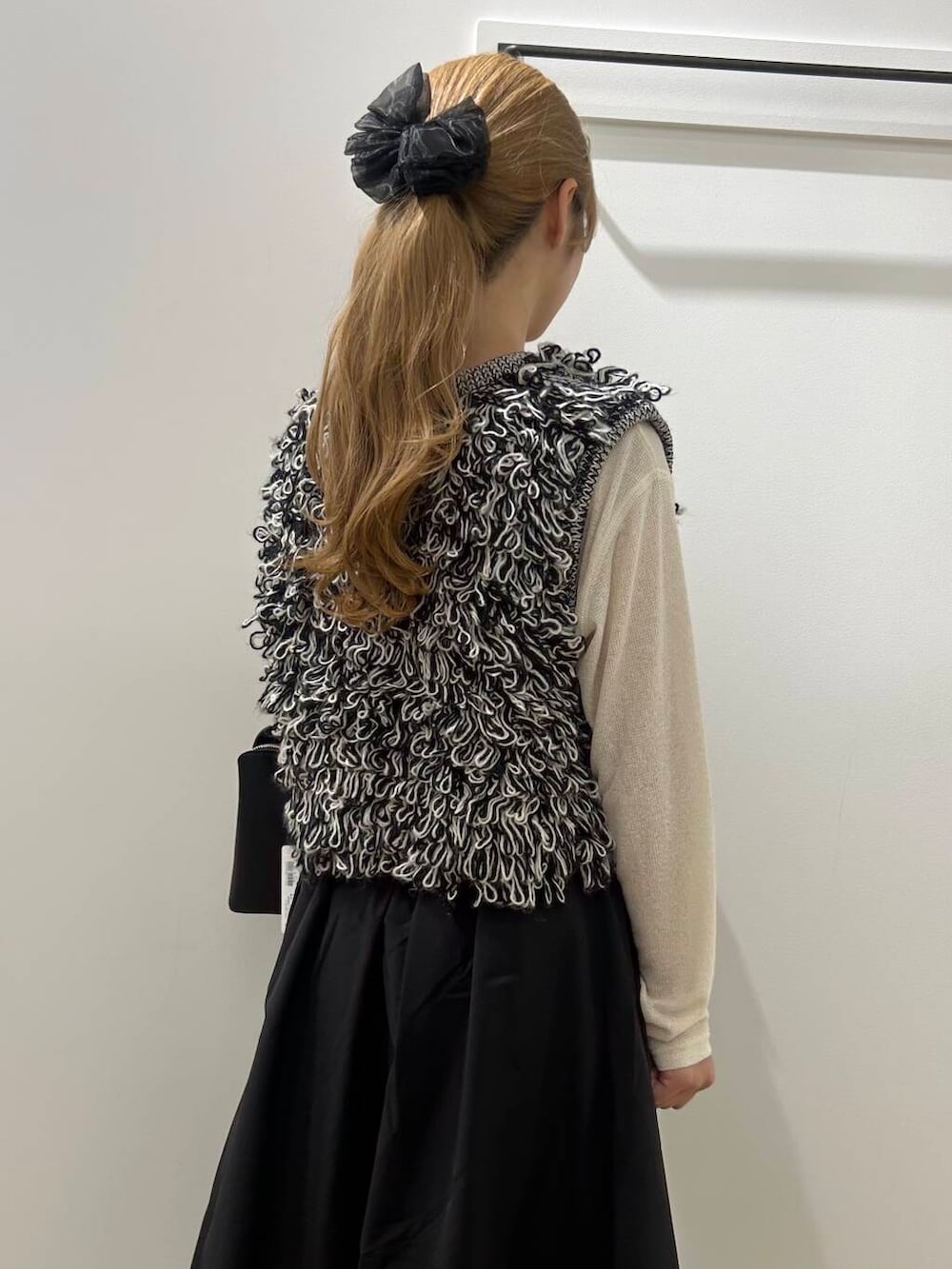 ブラック系のベスト、ブラック系のスカート、ブラック系のブーツを着用したレディースの秋コーディネートの2枚目の写真