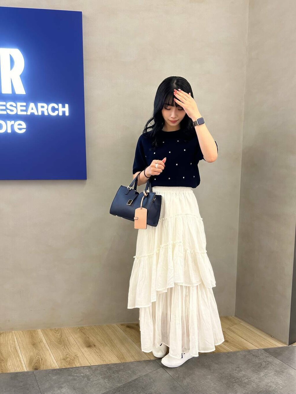 ブルー系のハンドバッグ、ブルー系のニット/セーター、ホワイト系のスカートを着用したレディースの春コーディネートの2枚目の写真