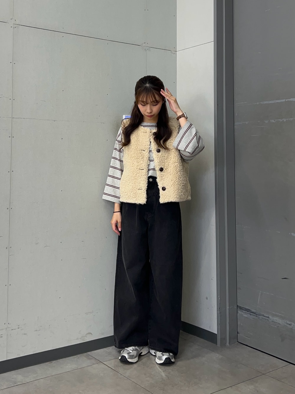グレー系のTシャツ/カットソー、ベージュ系のダウンベスト、ブラック系のデニムパンツを着用したレディースの秋コーディネートの2枚目の写真