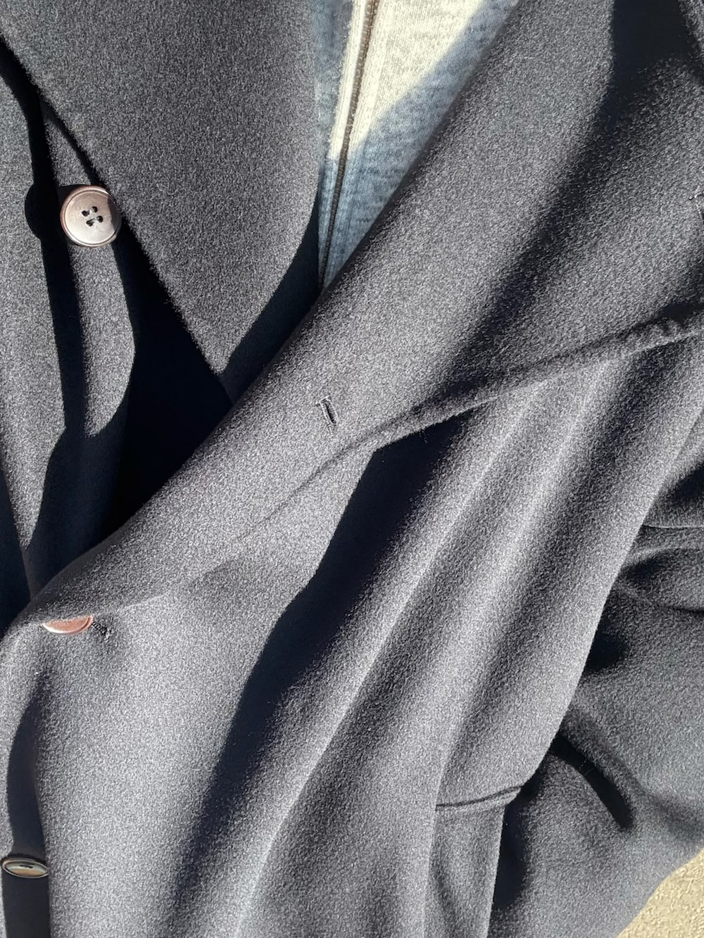 ブルー系のトレンチコート、グレー系のパーカー、ブラック系のスラックスを着用したメンズの秋コーディネートの4枚目の写真