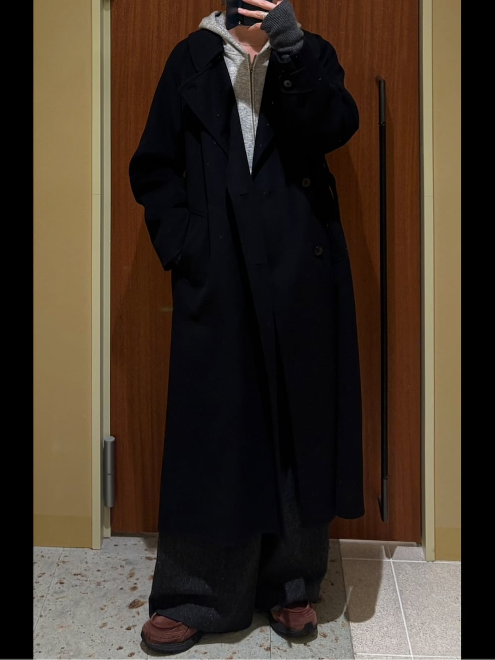 ブルー系のトレンチコート、グレー系のパーカー、ブラック系のスラックスを着用したメンズの秋コーディネートの2枚目の写真