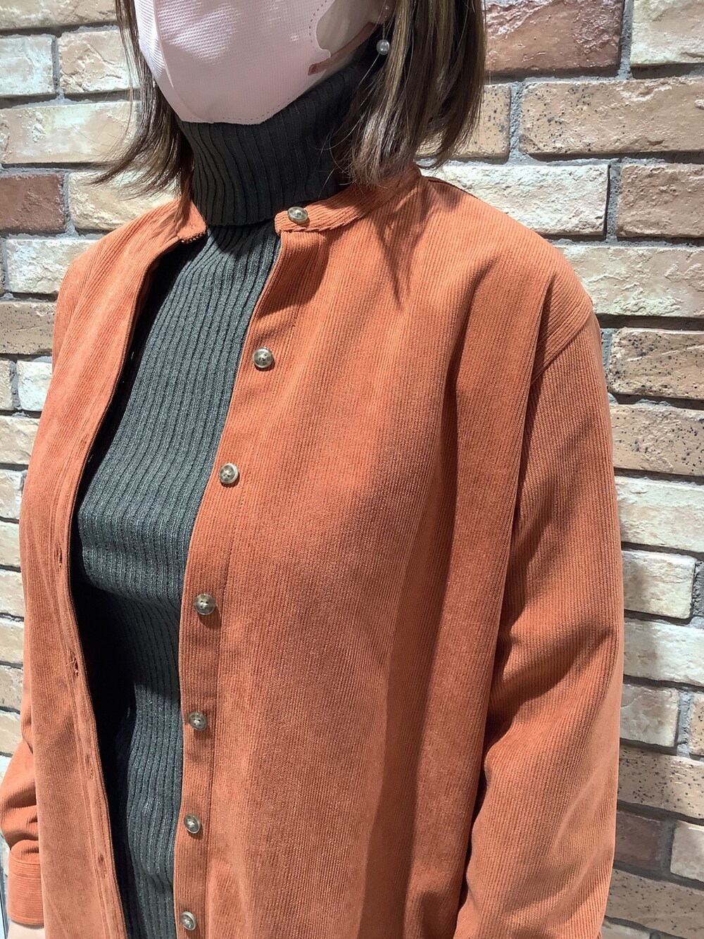 オレンジ系のシャツ/ブラウス、グリーン系のニット/セーターを着用したレディースの冬コーディネートの2枚目の写真